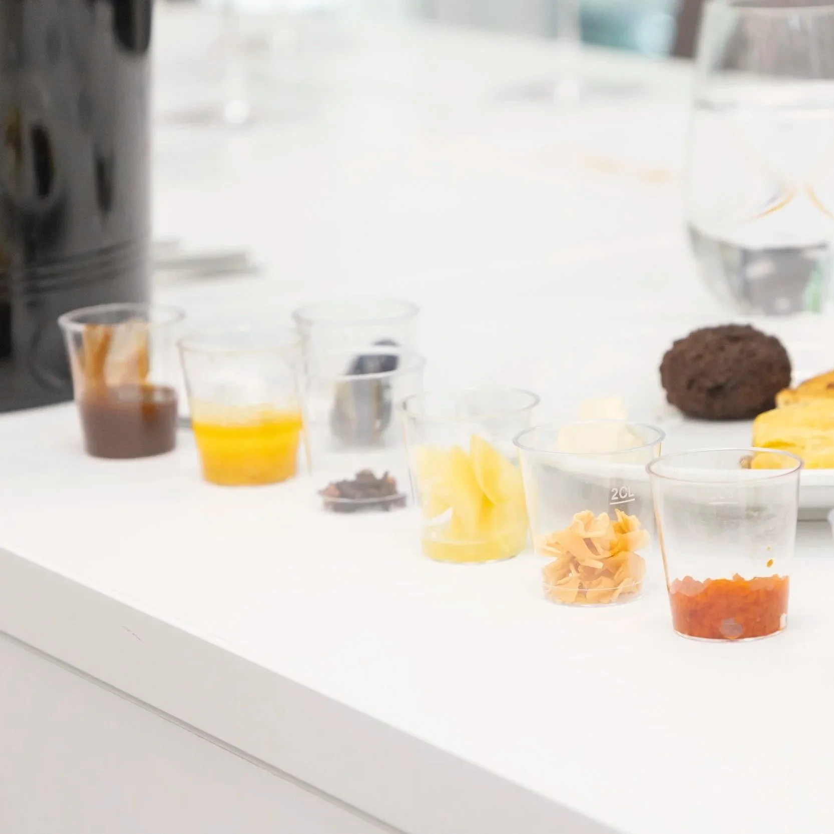 A selection of tropical food tasting samples, served in small clear vessels.