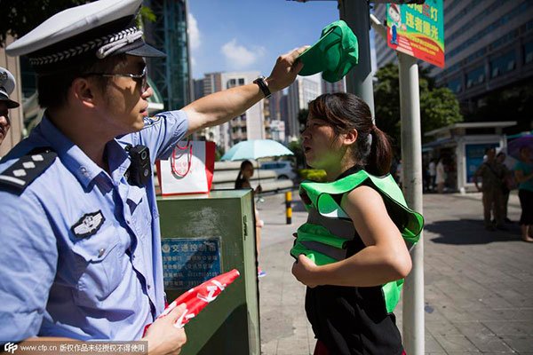 A policeman puts a green hat on a girl's head. [Photo by Chen Wencai from Western China Metropolis Daily/CFP]