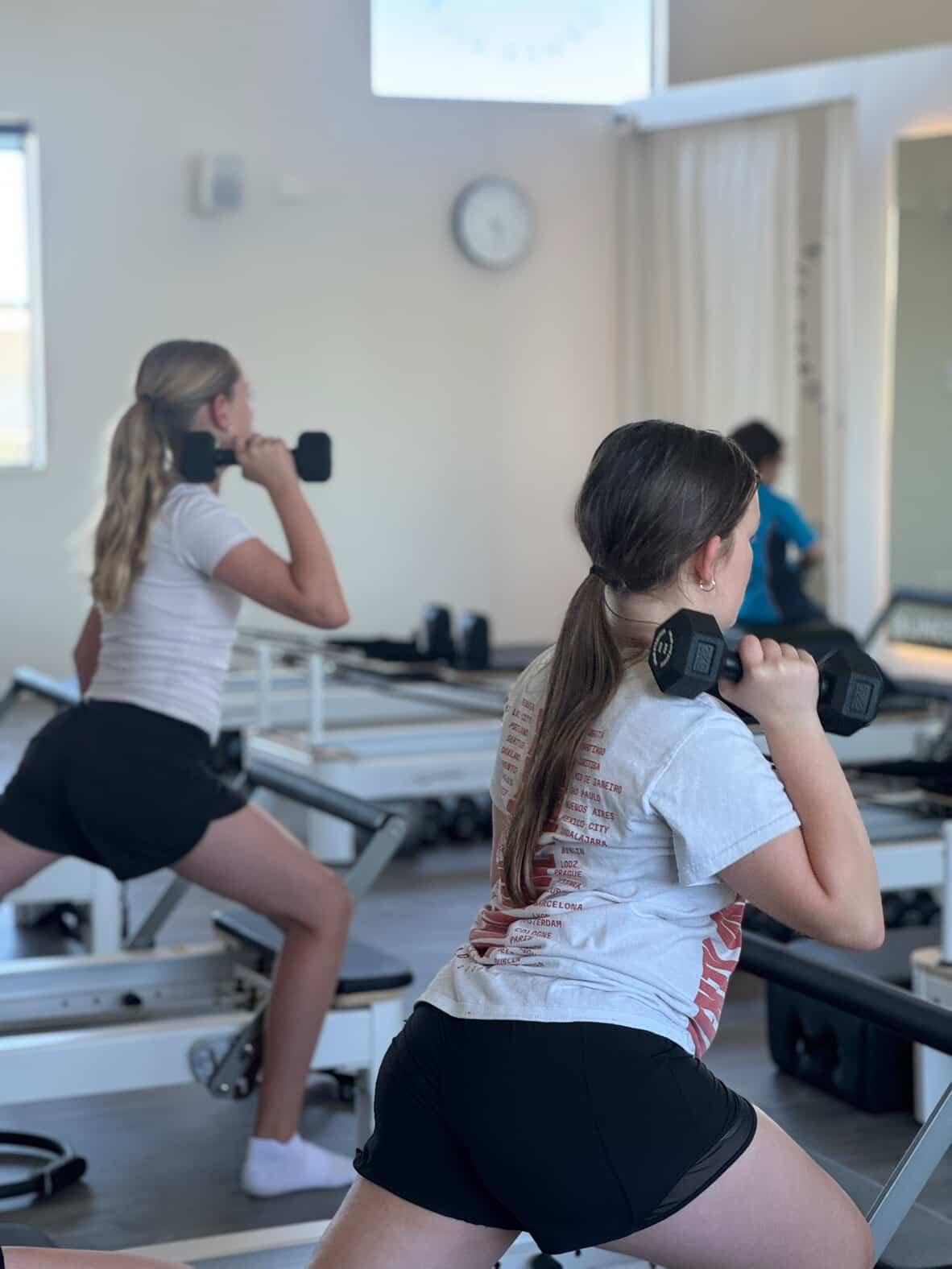 Image shows 2 teenage girls participating in a reformer pilates class at Lincoln Loft designed specifically for teenagers.