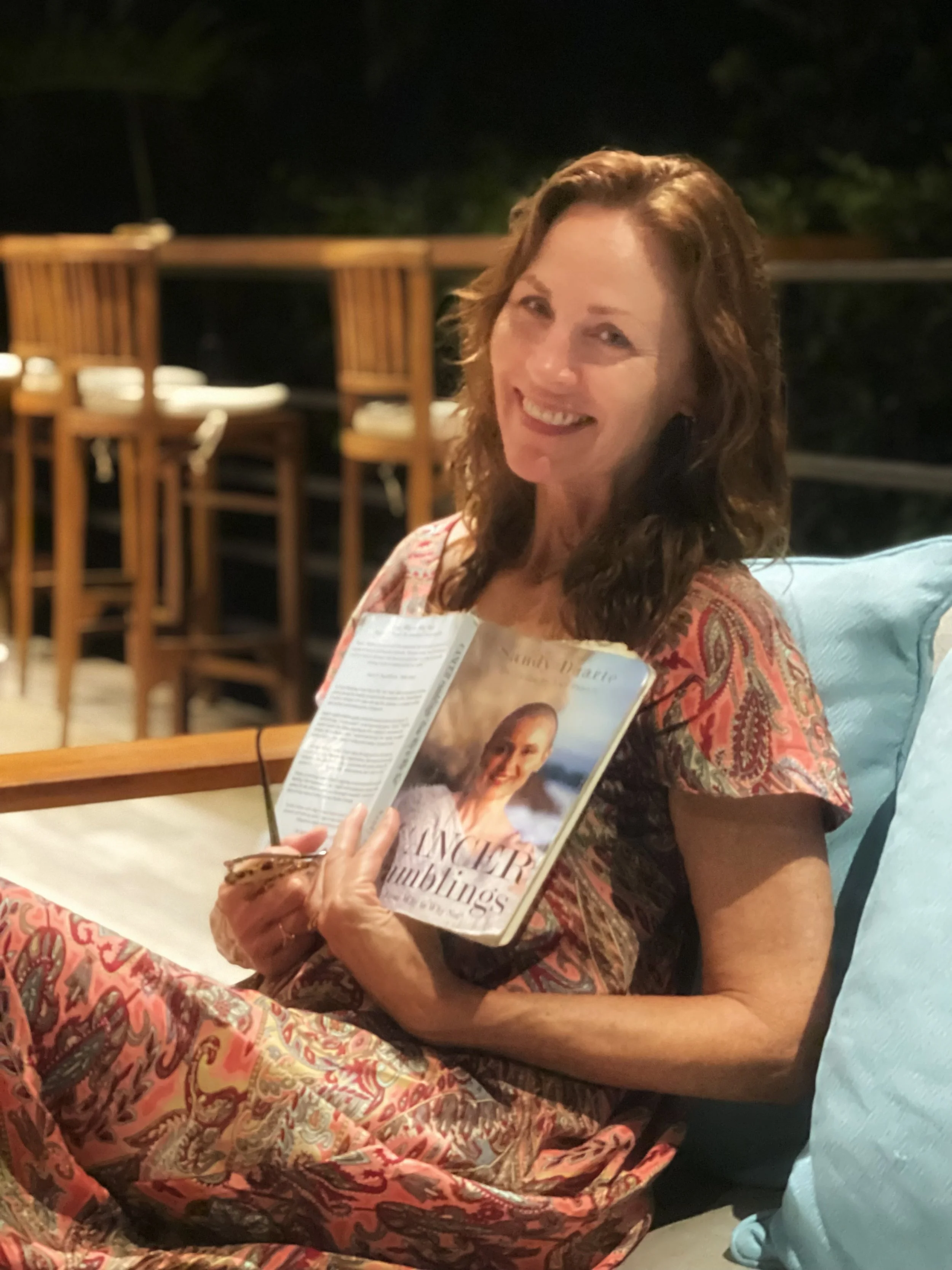 Kim Starzick, founder of Well Being Costa Rica, is a wellness leader and retreat facilitator dedicated to holistic healing, personal growth, and transformational experiences in nature-based settings. She is pictured with Cancer Ramblings, a book by S