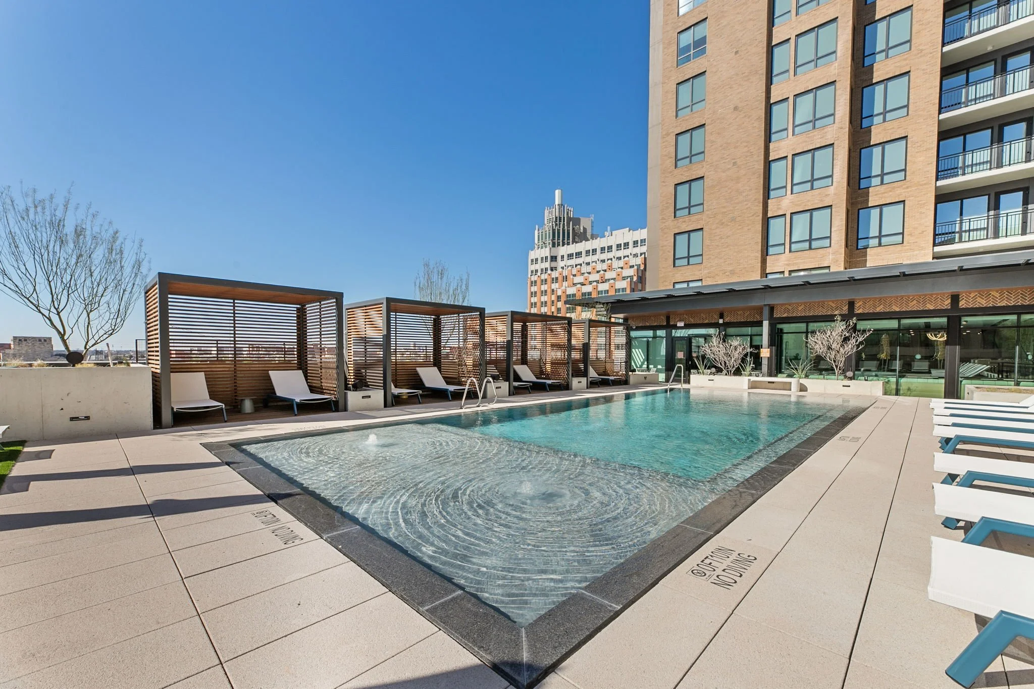 Continental Residences rooftop pool with lounge chairs and urban skyline in background