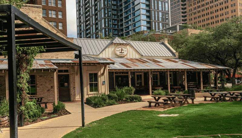 Animated GIF showing outdoor park scene at Legacy Park with walking paths, green trees, and people enjoying the space