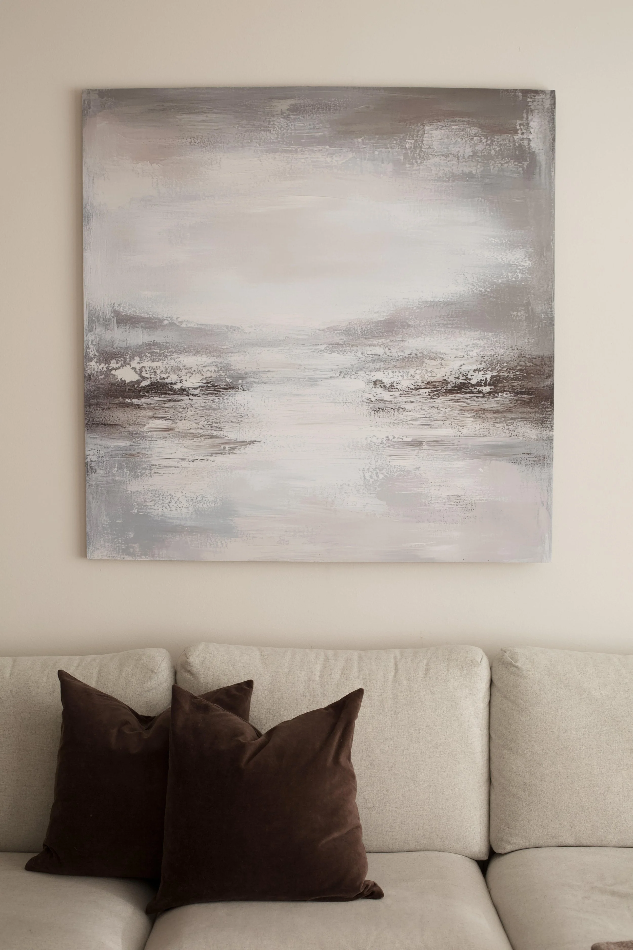 Samoja luonnonsävyjä toistava suuri taidetaulu luo rauhoittavan tunnelman ja täydentää seesteisen kokonaisuuden.