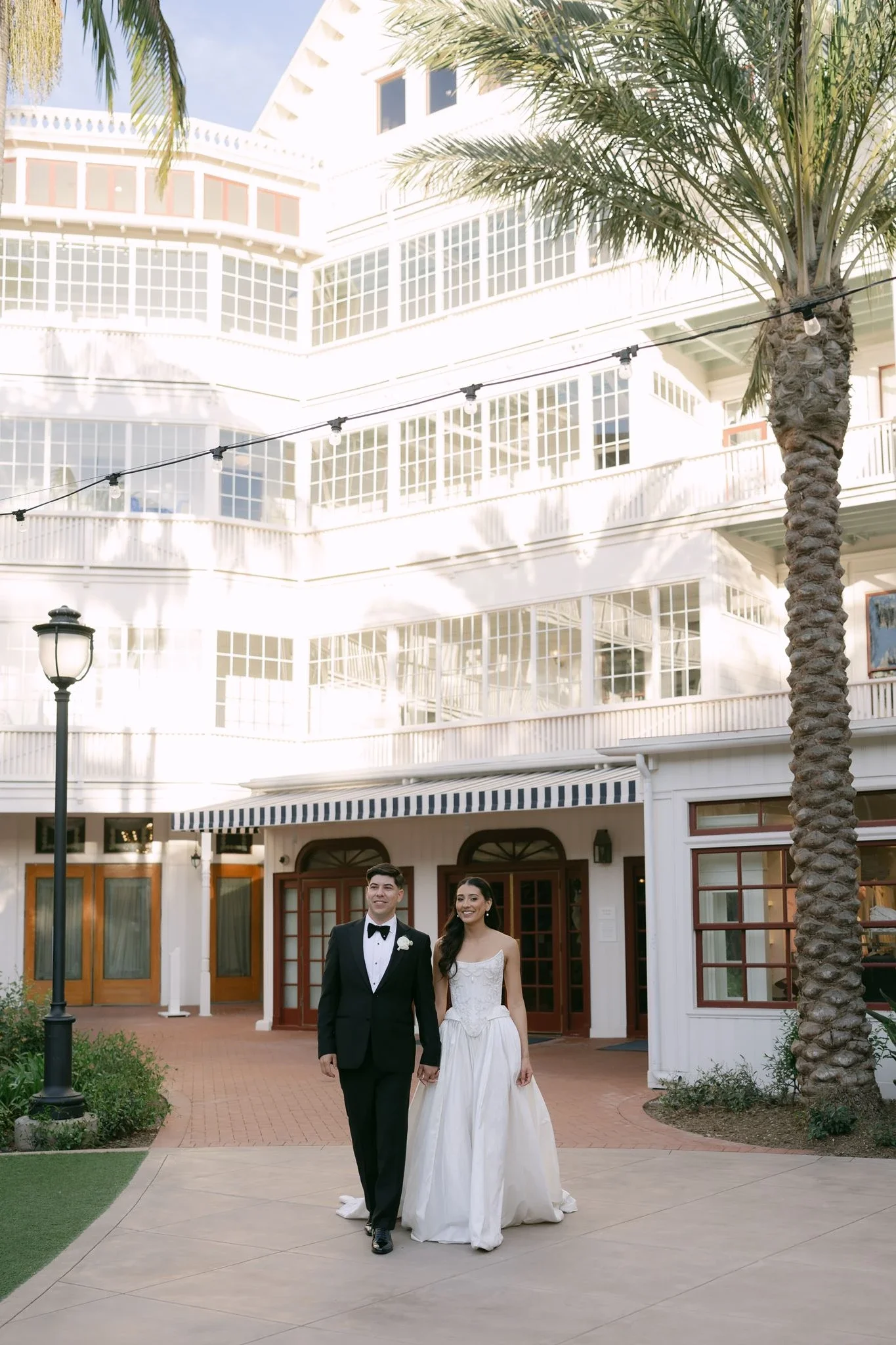 hotel-del-coronado-wedding-couple-walking-hotel-courtyard.webp