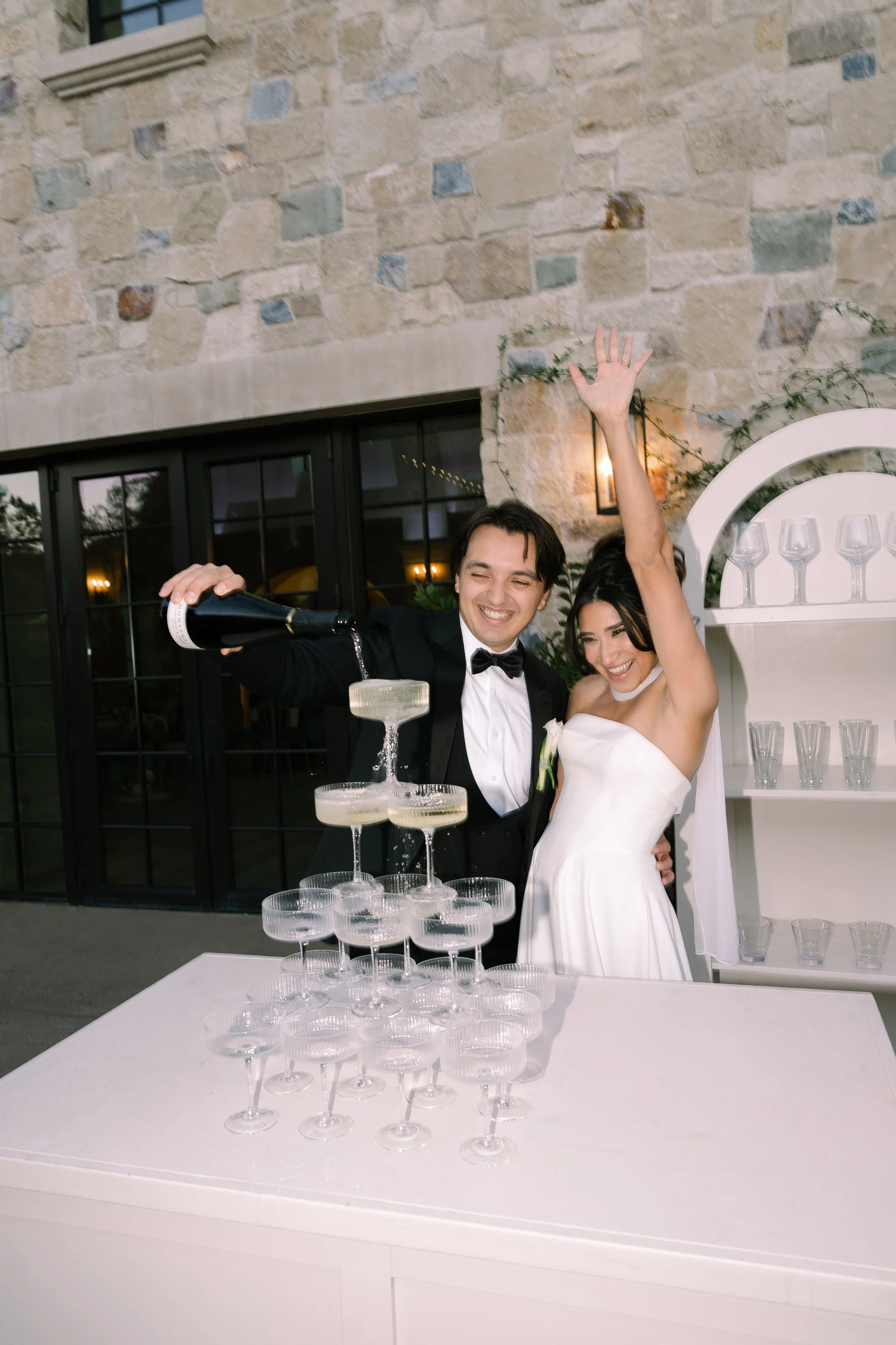 A newlywed couple celebrating with champagne and a champagne Tower at their wedding reception.