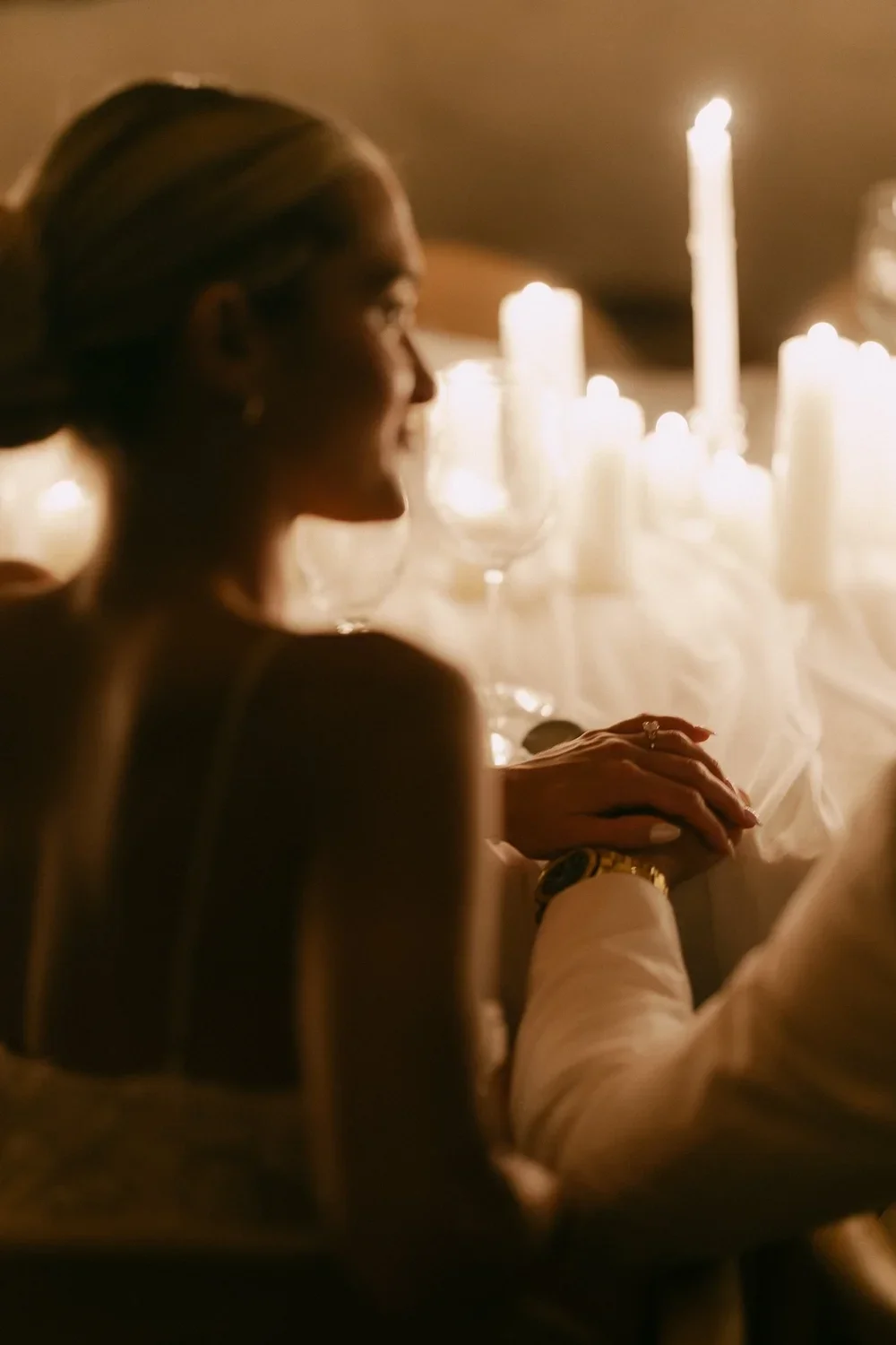 An intimate moment shared by a couple during their destination wedding in Tulum, with bride's hand gently put onto the groom's during their candlelit reception.