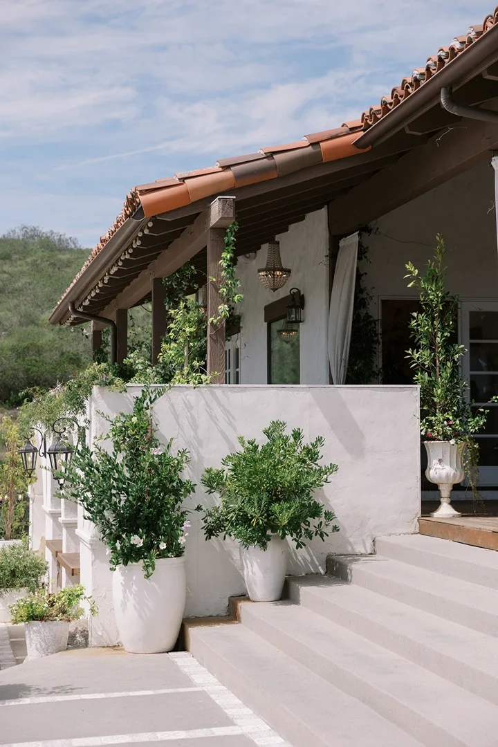 Covered patio at Jeune Perché Estate with a terracotta-tiled roof, white stucco walls, and potted greenery lining the steps