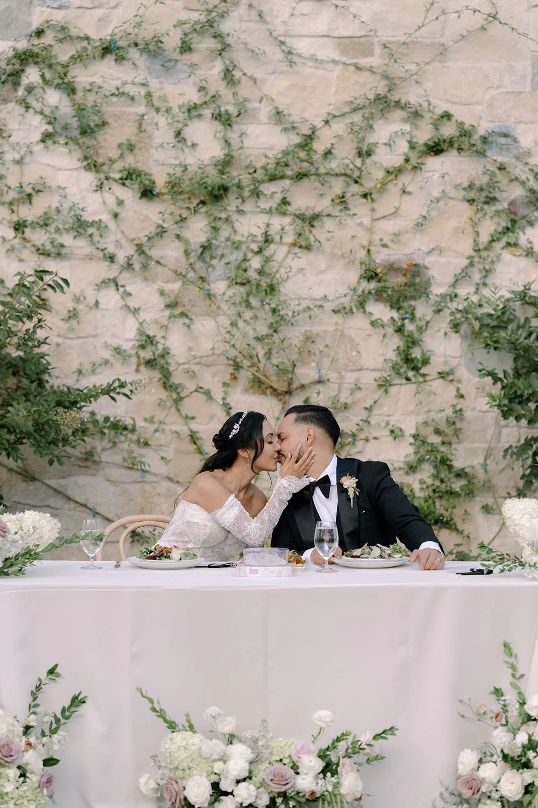 Bride and groom kissing at their table during their reception at Monserate Winery