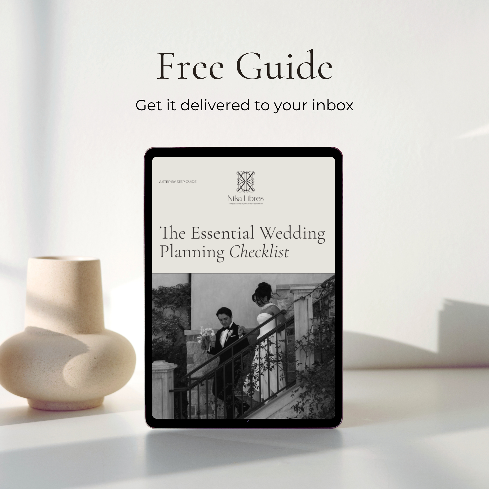 A digital tablet displaying a wedding planning checklist app next to a beige vase on a white surface, with a plain white background.