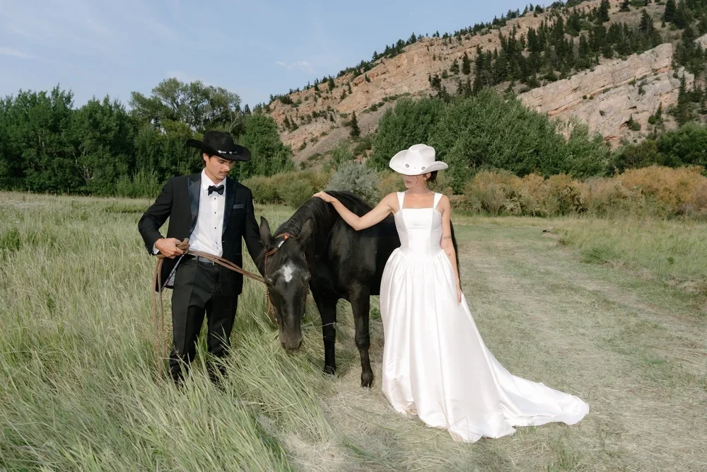 Destination wedding photographer capturing a bride and groom in a scenic outdoor location, walking with a horse amidst mountains, showcasing unique wedding moments in a outdoor Montana setting