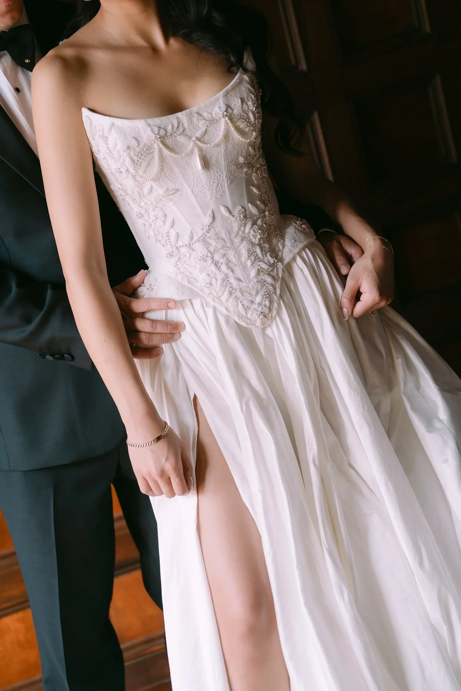 Close-up of bride’s wedding dress with intricate detailing, while the groom’s hand rests gently on her waist, highlighting the intimate connection between the couple during their Hotel Del Coronado wedding