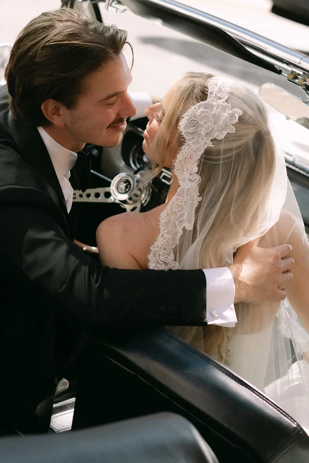 Bride and groom in a romantic wedding portrait inside a vintage car
