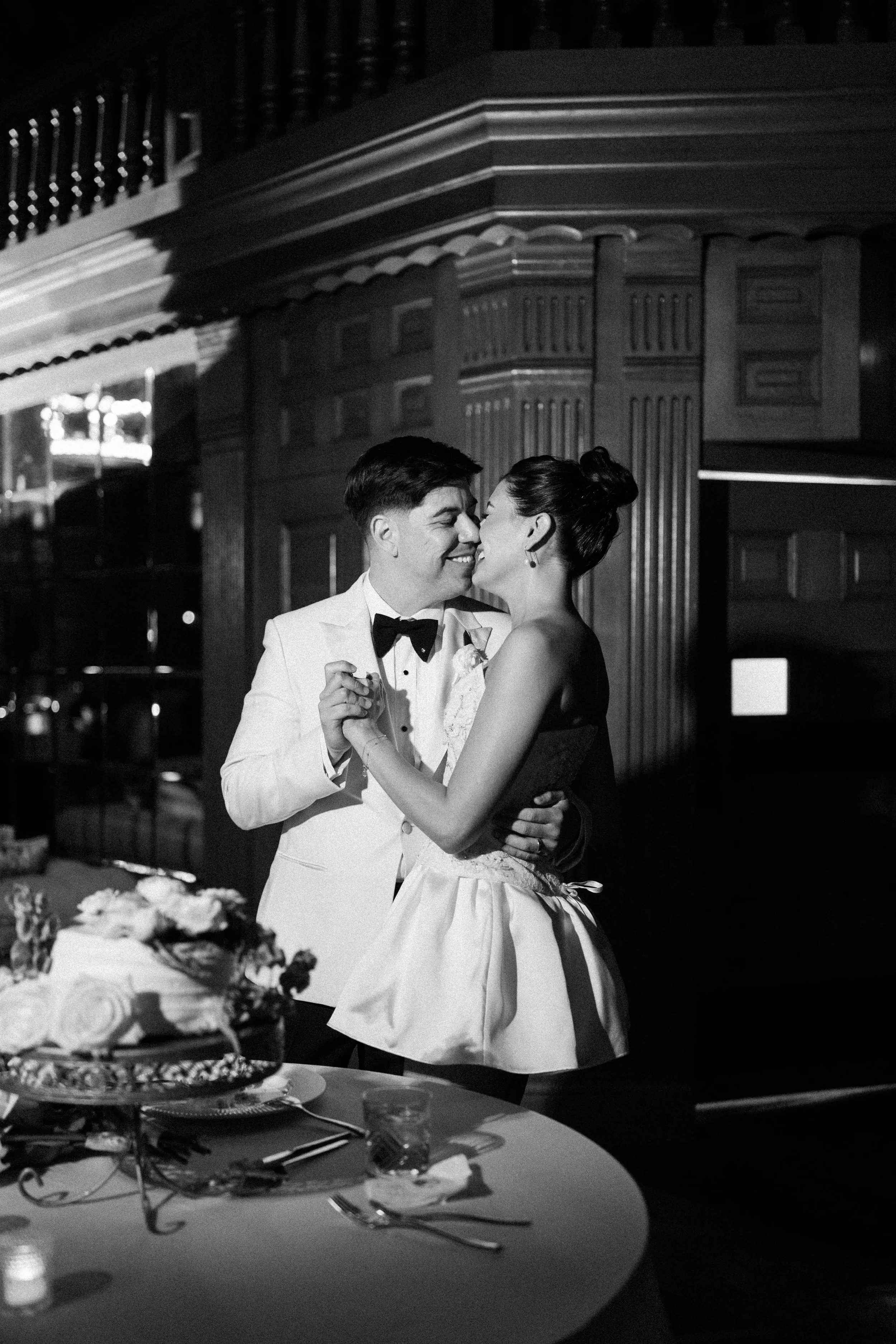 A couple sharing a kiss after cutting their wedding cake at the Hotel Del Coronado wedding in San Diego. Black and white photo captured on film