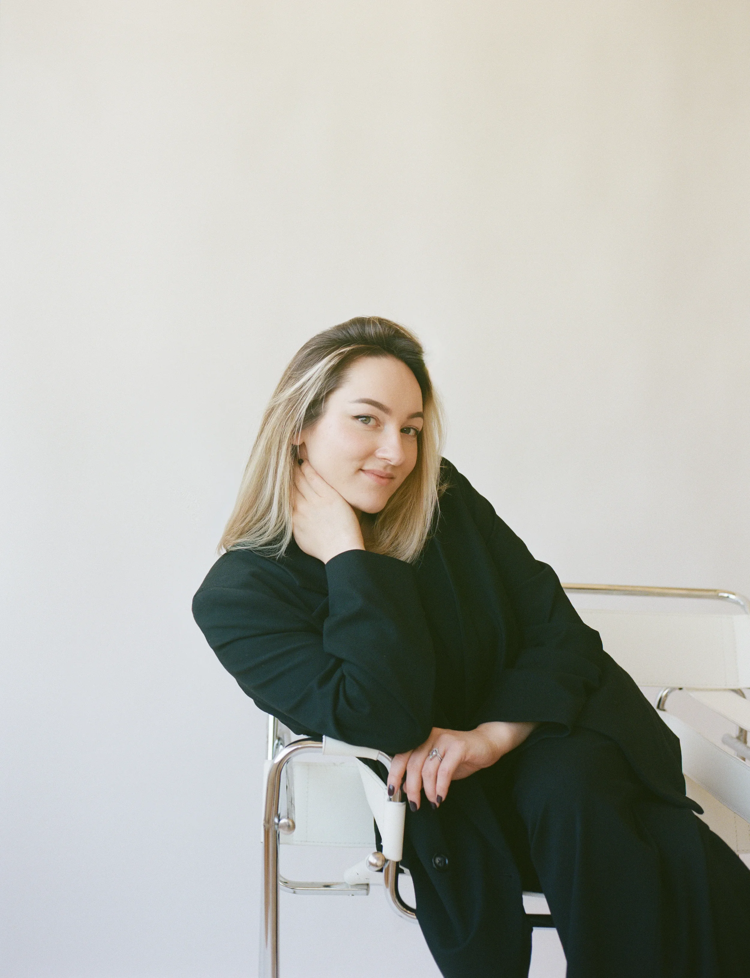 Portrait of Jeune Perché Estate wedding photographer Nika Libres seated in a black suit against a soft neutral backdrop