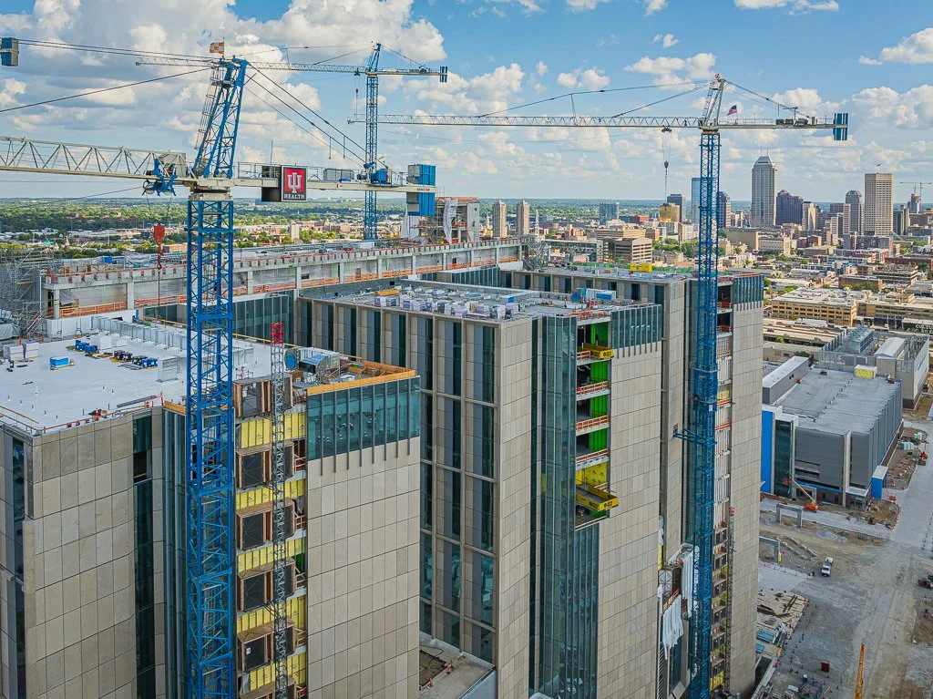 A construction site on top of a high-rise building with cranes and city skyline in the background.