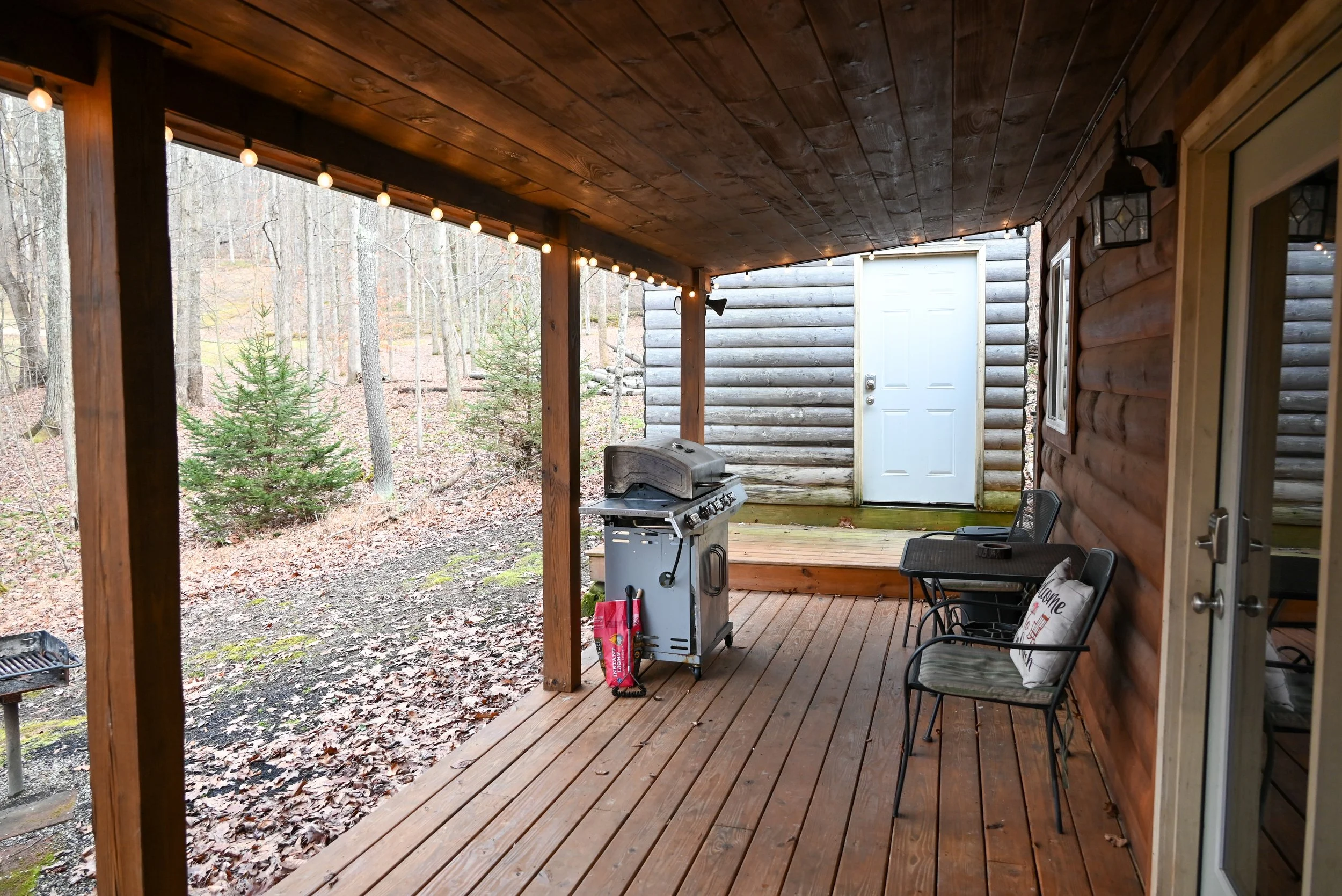 Secluded cabin porch with grill and seating overlooking the wooded landscape at Beary Cozy Cabin in Hocking Hills.
