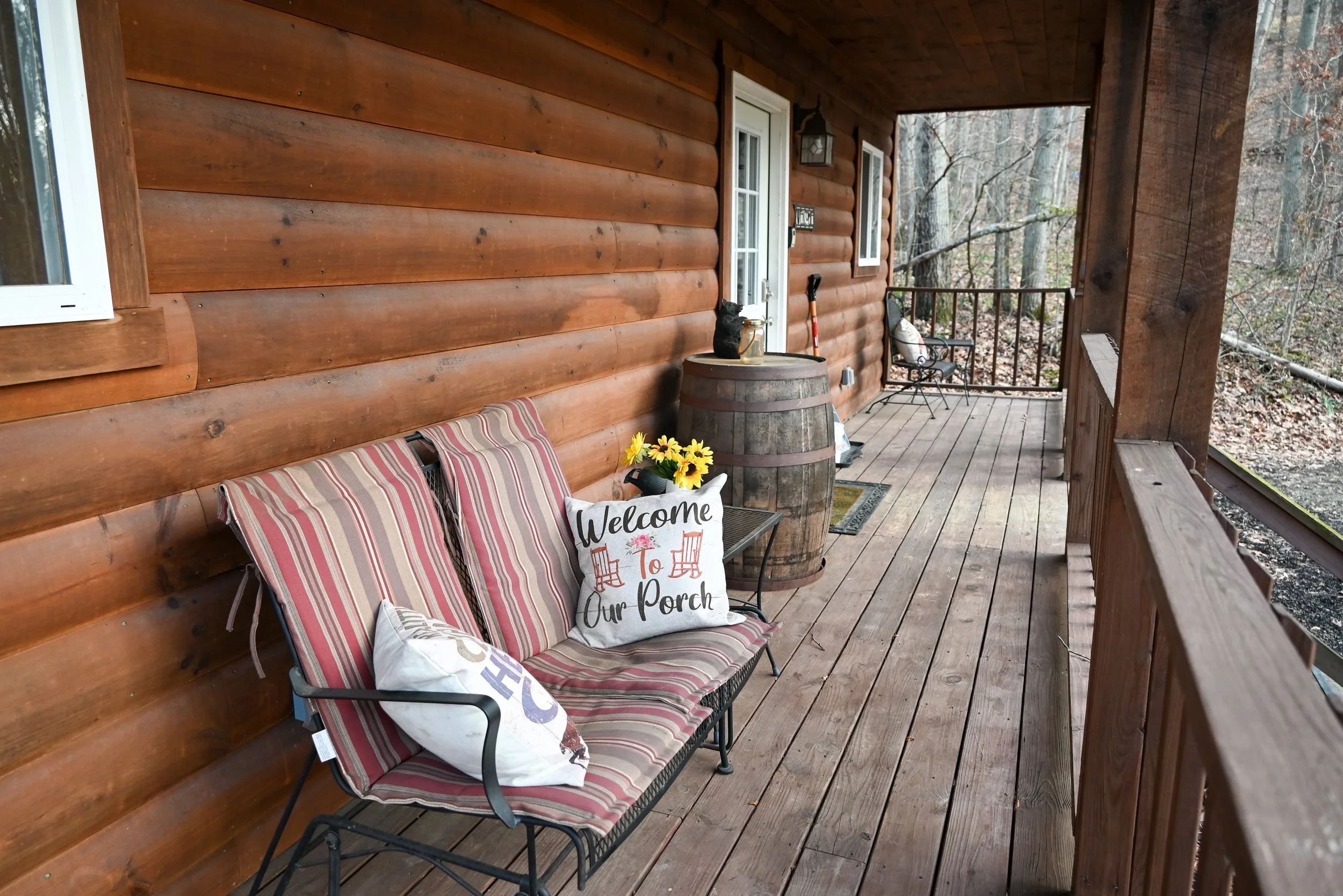 Covered porch with lounge seating and forest views at Beary Cozy Cabin, providing guests with a quiet place to unwind in Hocking Hills.