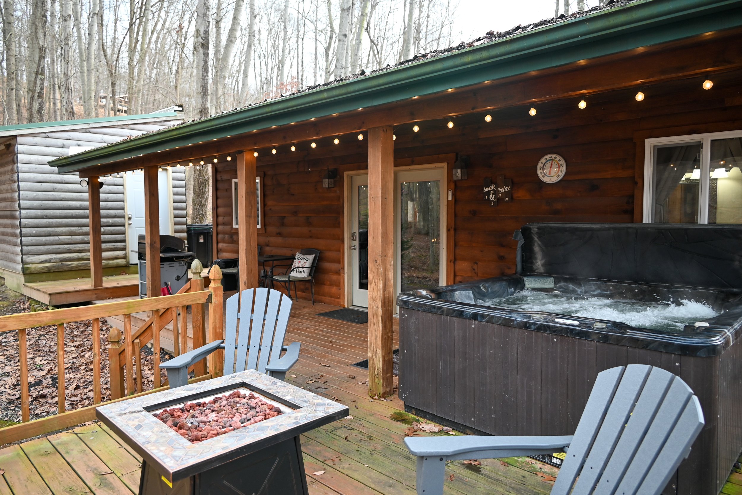 Romantic cabin deck at Beary Cozy Cabin featuring a bubbling hot tub, cozy seating, and warm string lights—perfect for couples enjoying a Hocking Hills getaway.