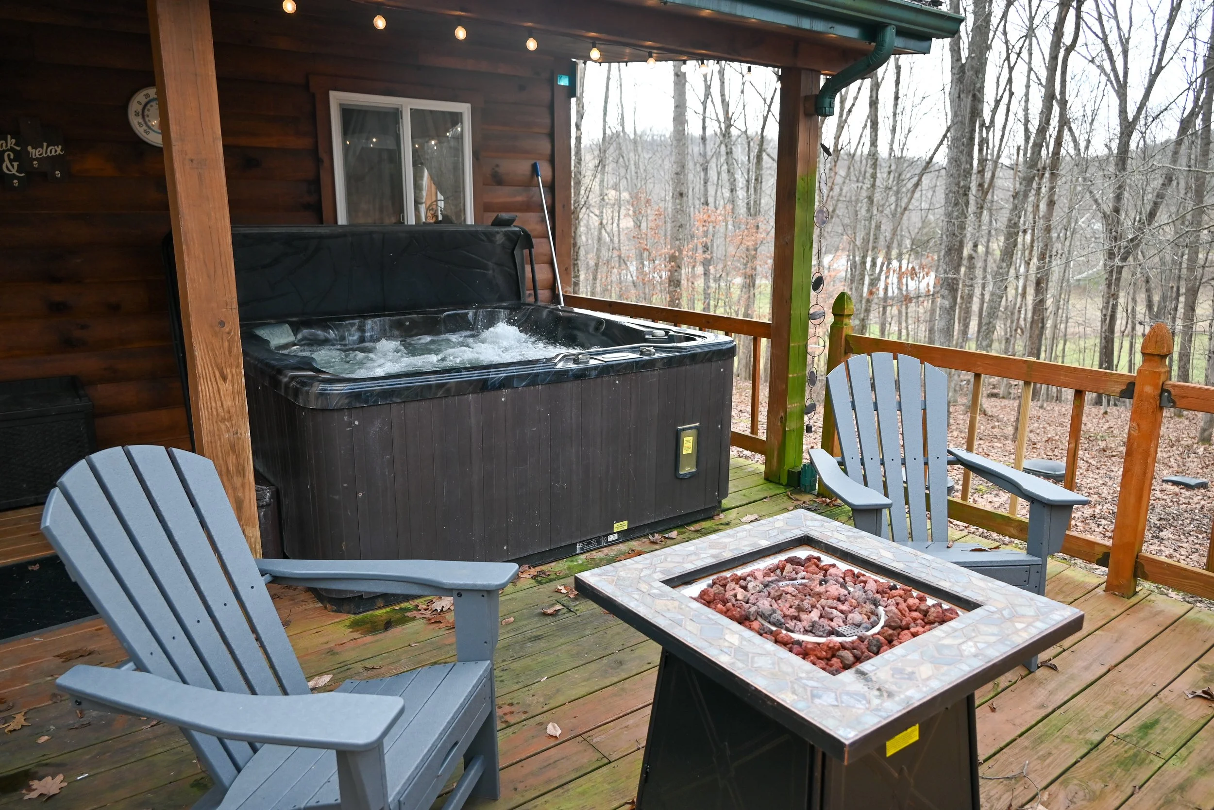 Cozy hot tub and fire table deck at Beary Cozy Cabin, offering couples a romantic space to relax under the trees in Hocking Hills.