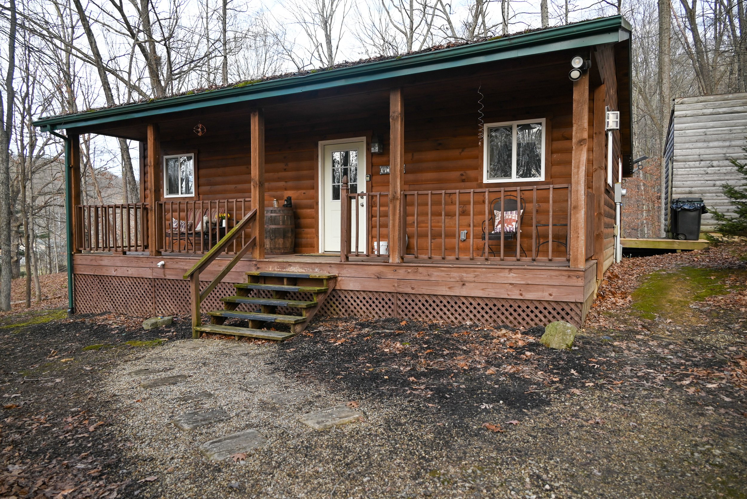 Rustic log cabin exterior with covered front porch at Beary Cozy Cabin, a private Hocking Hills rental surrounded by trees.