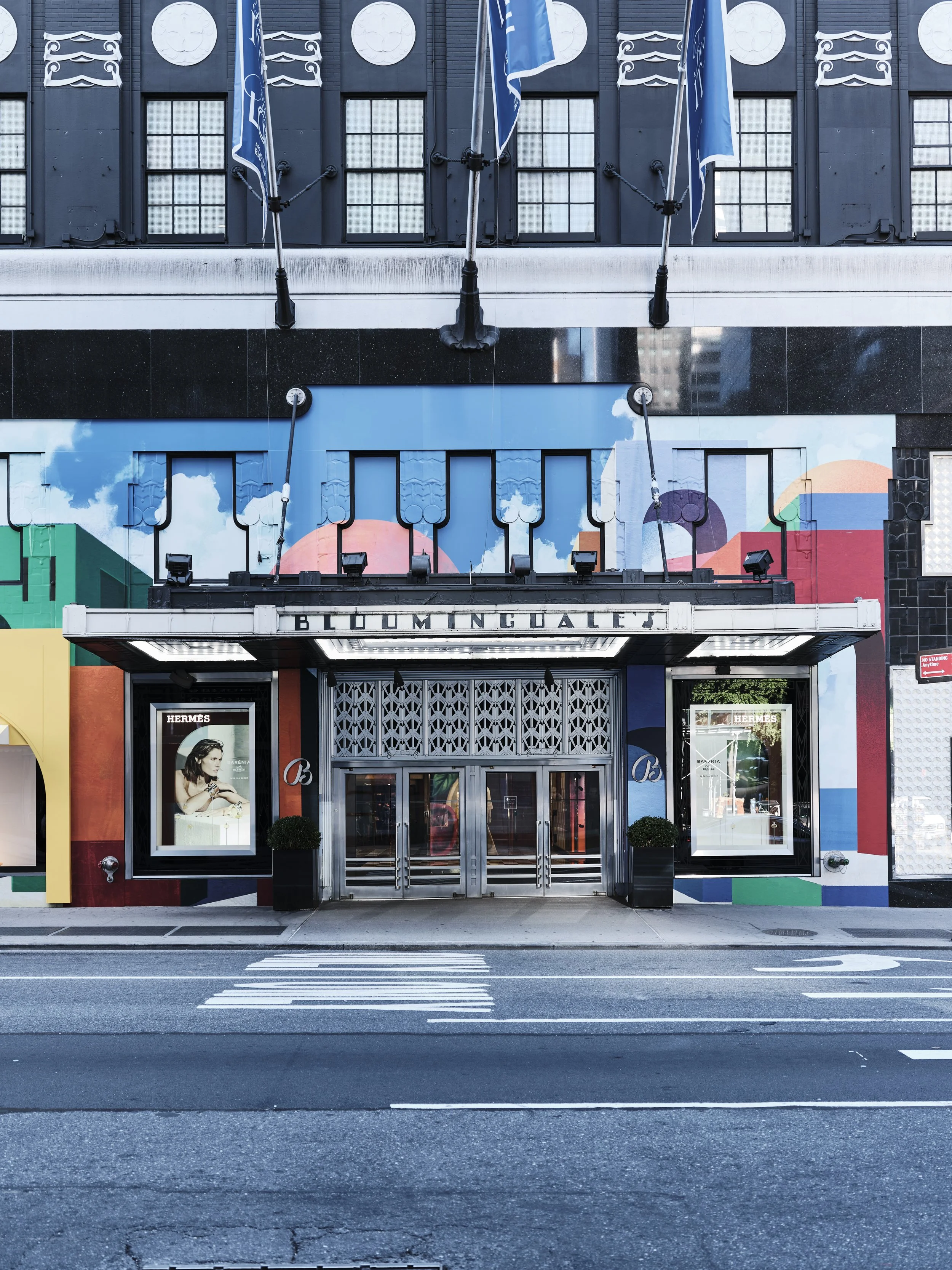 Front of Bloomingdale's store with a colorful mural, advertising for Hermès, and an entrance with glass doors.