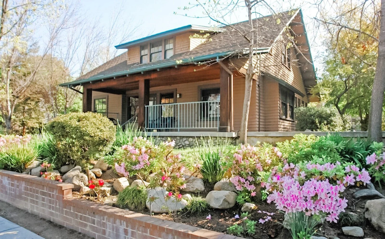 My office: a two-story brown craftsman cottage in Pasadena with green and pink floral landscaping in front.