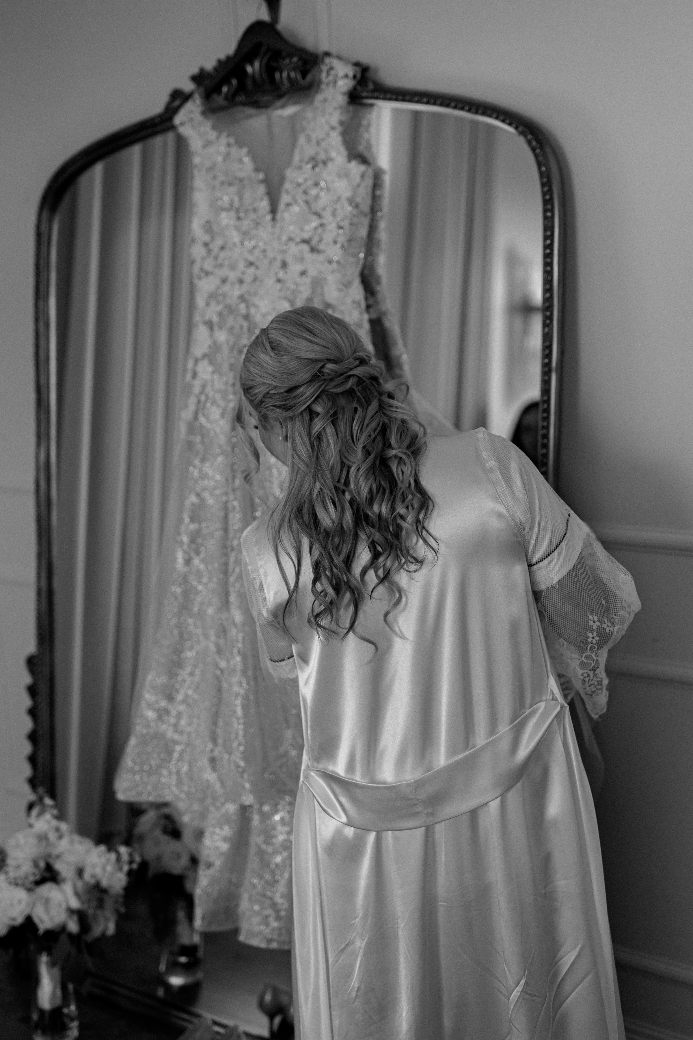 Founder Amber on her wedding day, wearing a silk robe and preparing beside her gown — a quiet, intentional moment capturing the beauty and anticipation behind Beam & Bramble’s creative vision