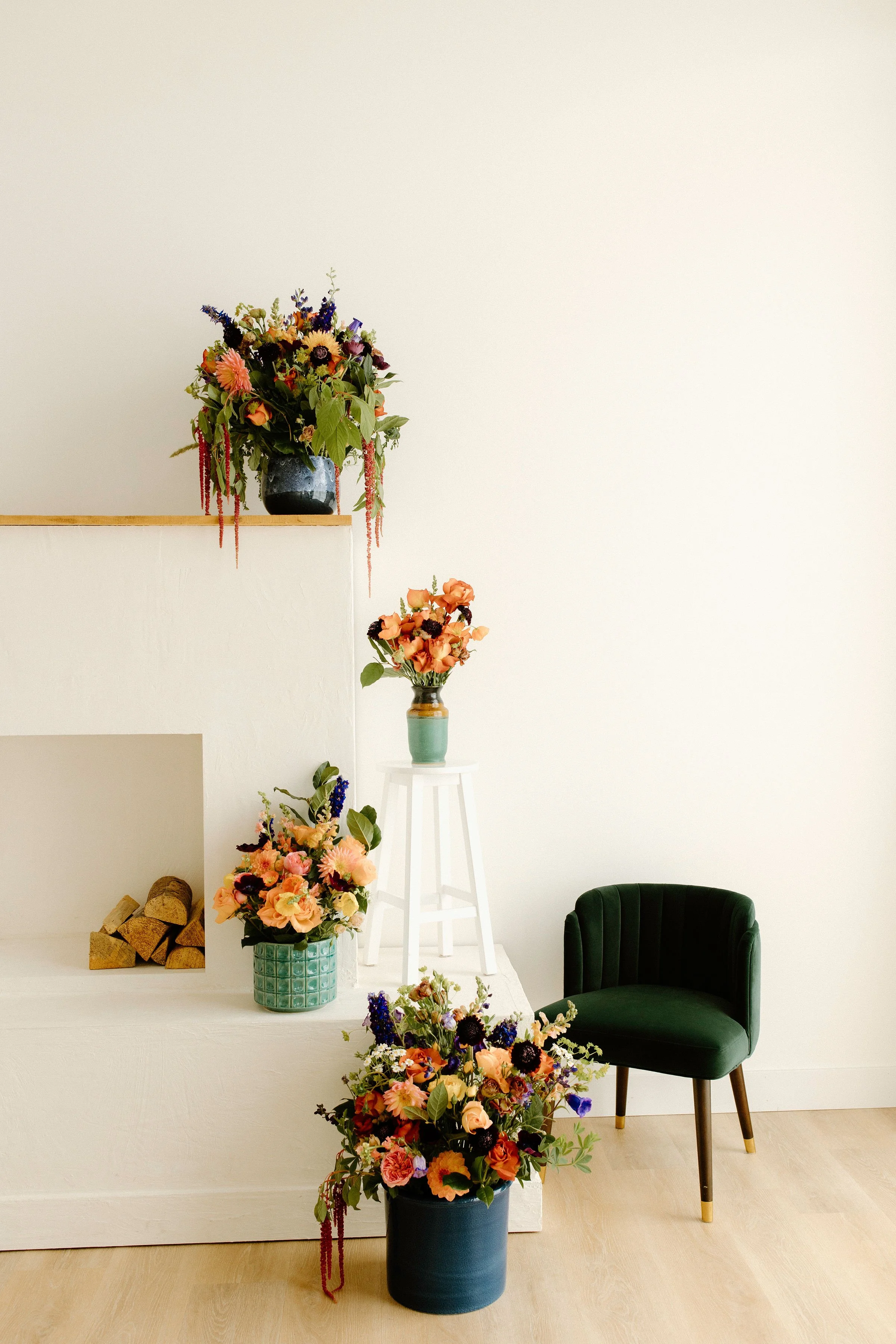 Three boutique floral arrangements styled on white pedestals in a minimalist studio, part of the Flora & Fare hospitality collection designed for lobbies, retail, and boutique spaces.