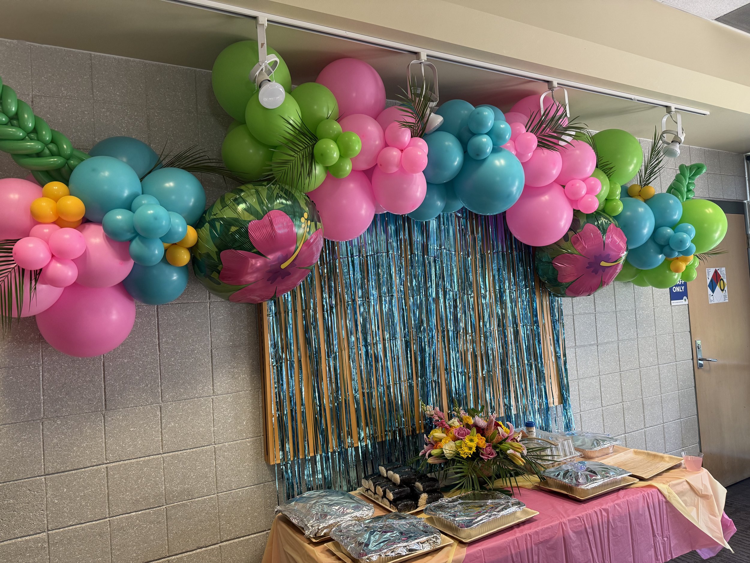 Hawaiian-themed birthday party designed by Beam & Bramble, featuring tropical florals, balloon arch, colorful streamers, and festive tablescapes — praised by Katie O. for creativity and cohesion