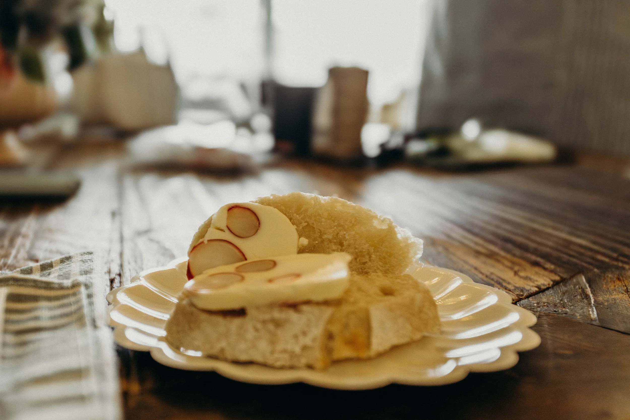 Slice of homemade sourdough bread baked by local artisan Jenn Hughes with radish butter terrine on a decorative white plate on a wooden table.