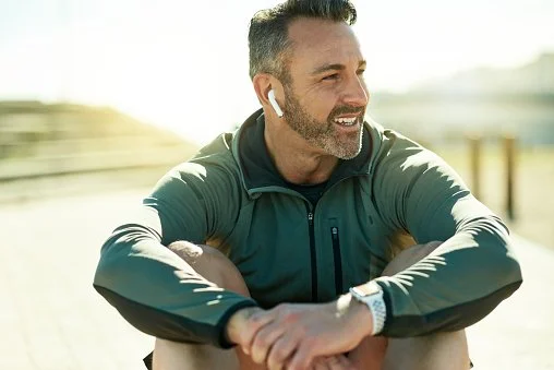 A man outdoors wearing wireless earbuds, symbolizing Woodhaven Recovery’s recommended videos and music resources for families navigating recovery.