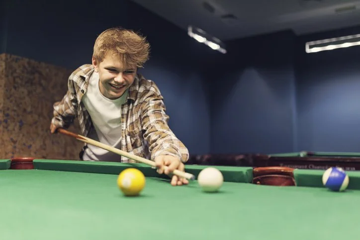 Resident playing pool indoors, engaging in fun recreational activities that support social connection and recovery.