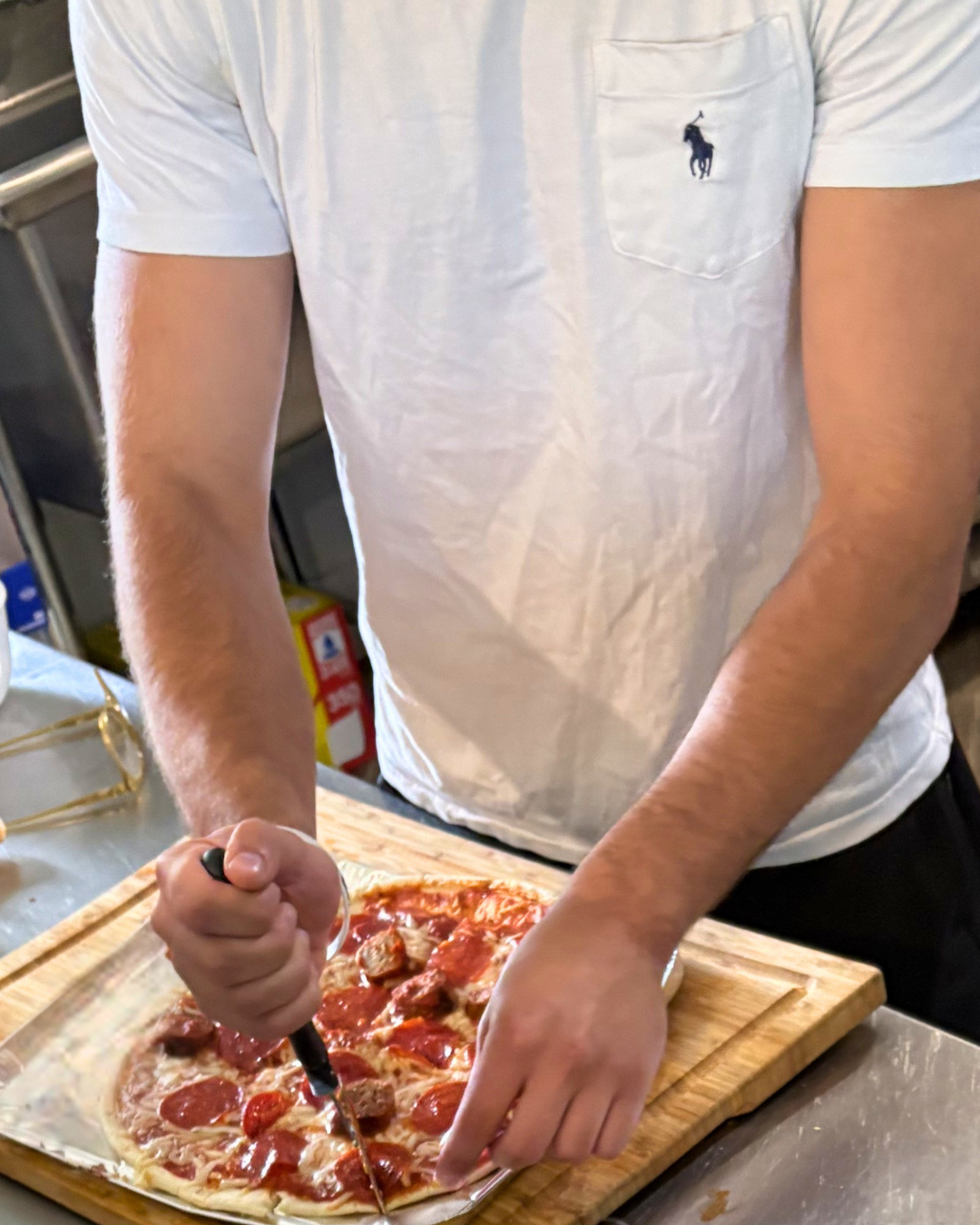 Young man at Woodhaven on Mulberry cutting homemade pizza during a shared meal at Woodhaven Recovery.