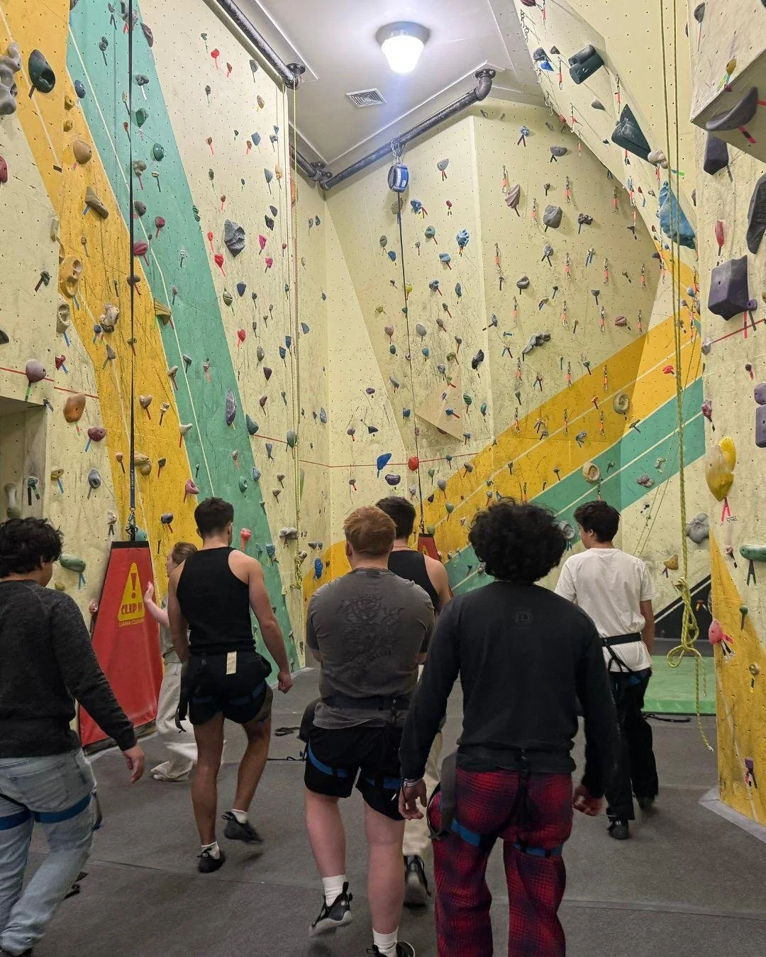 Teen boys prepare for an indoor rock climbing activity, building confidence, perseverance, teamwork, and healthy recreation in recovery.