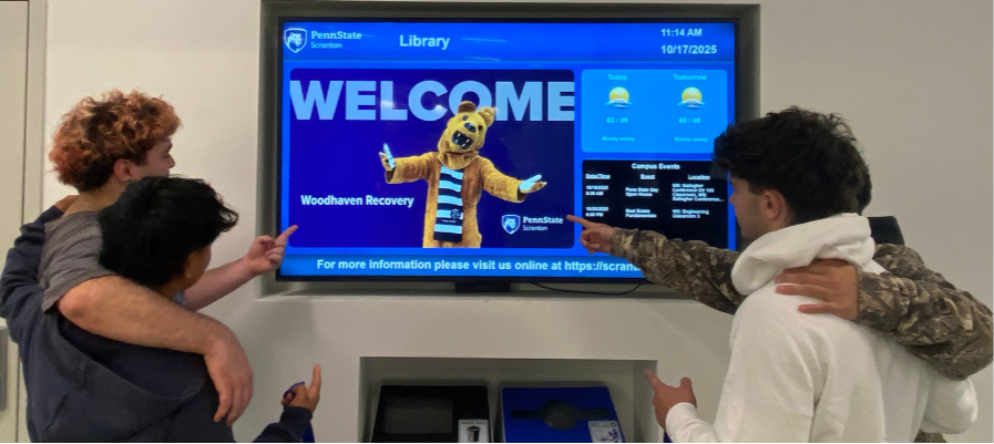 Woodhaven Academy students point to a welcome screen during a college campus visit.