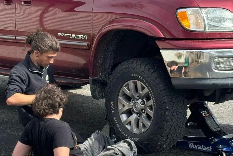 Woodhaven Prep student practices hands-on life skills by helping work on a vehicle during a Foundations for Success activity.