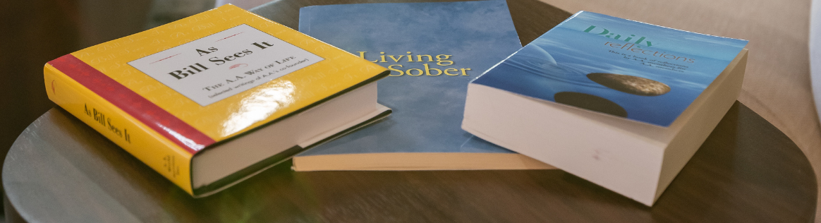 Recovery reading materials on a table at Woodhaven Recovery, including As Bill Sees It, Living Sober, and Daily Reflections.