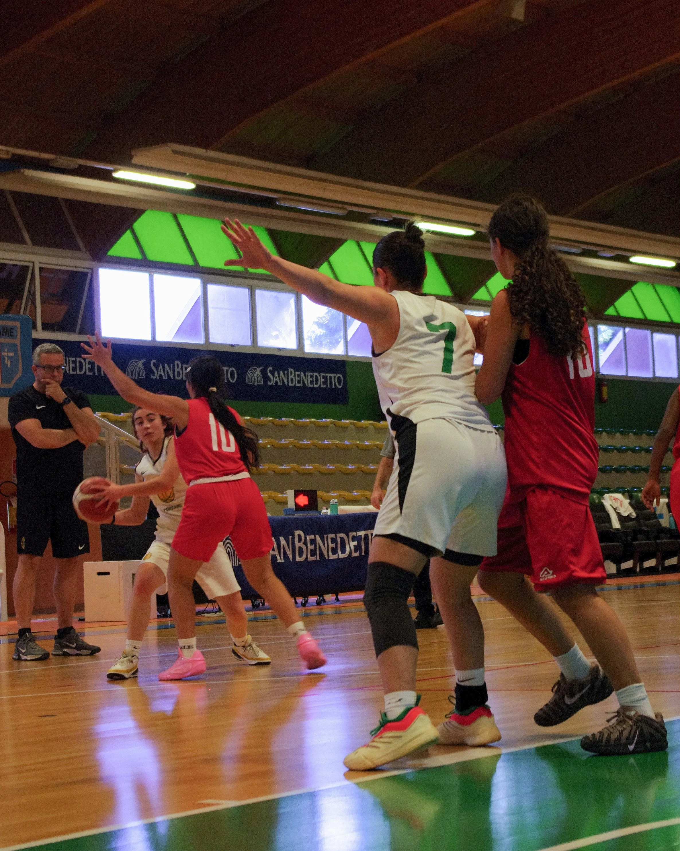 Giocatrici di basket femminile della pallacanestro ponzano in azione durante una partita indoor al Palacicogna, con pubblico e allenatore sullo sfondo.