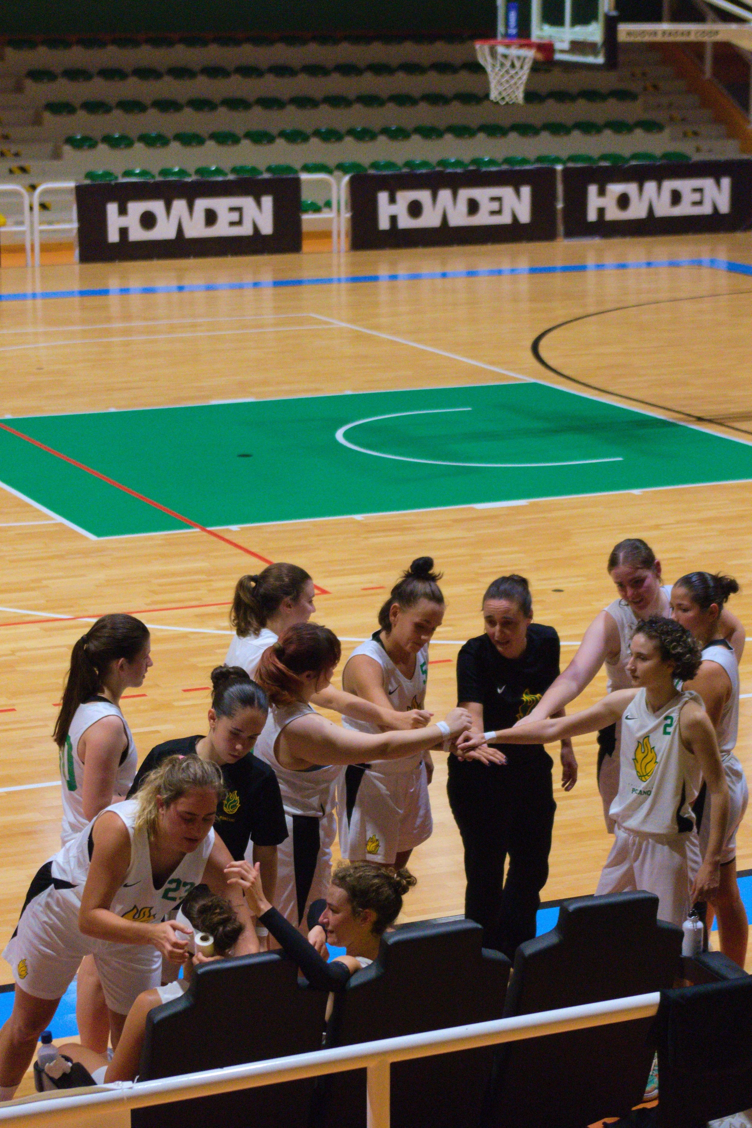 Giocatrici della promo femminile della pallacanestro ponzano nel Palacicogna, alcune sedute e altre in piedi intorno alla coach Lucija Drobac che è seduta, alcune si danno il cinque.