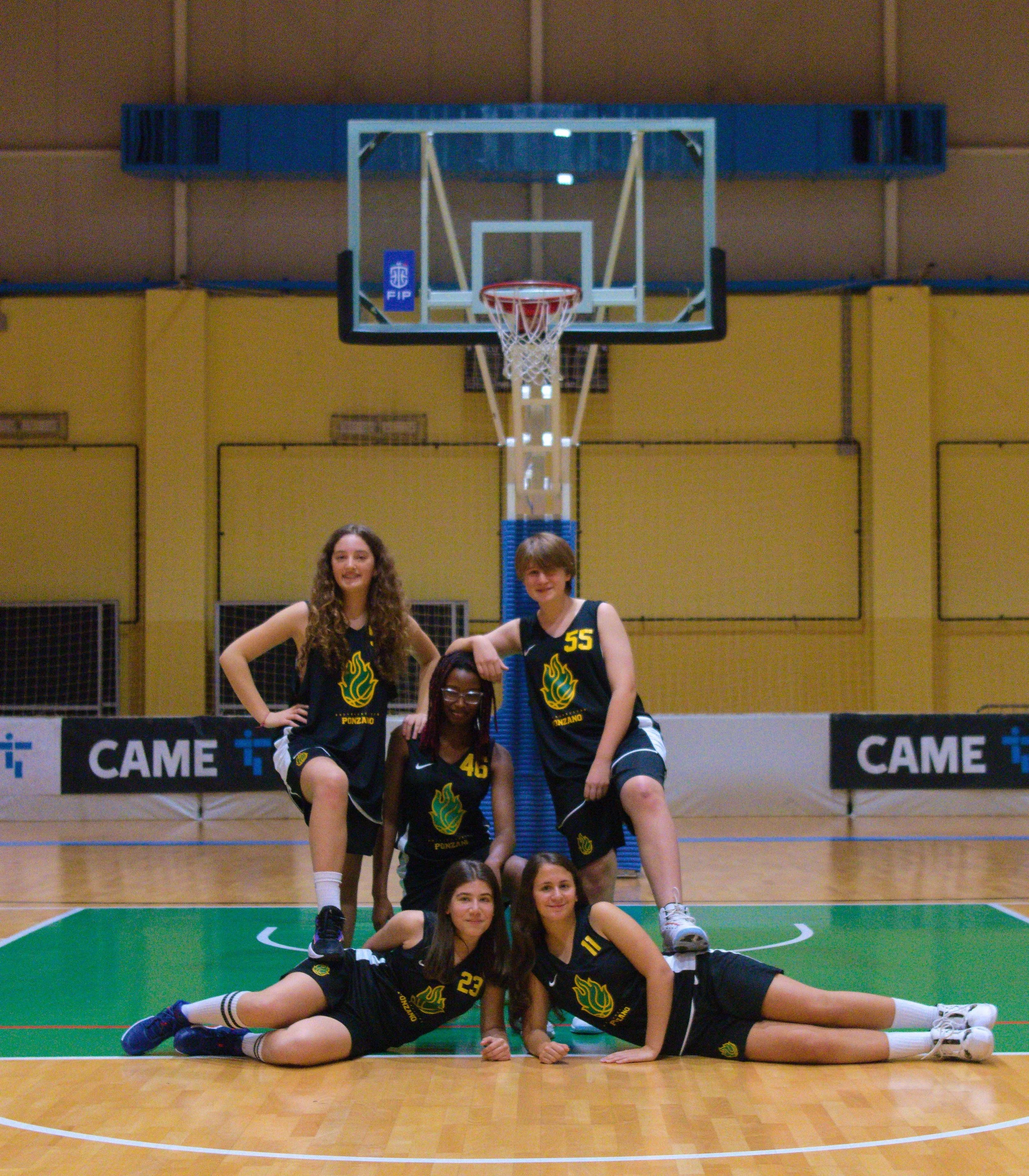 Gruppo di cinque giovani ragazze dell'under 14 femminile della pallacanestro ponzano in divisa di basket in un campo da pallacanestro indoor.