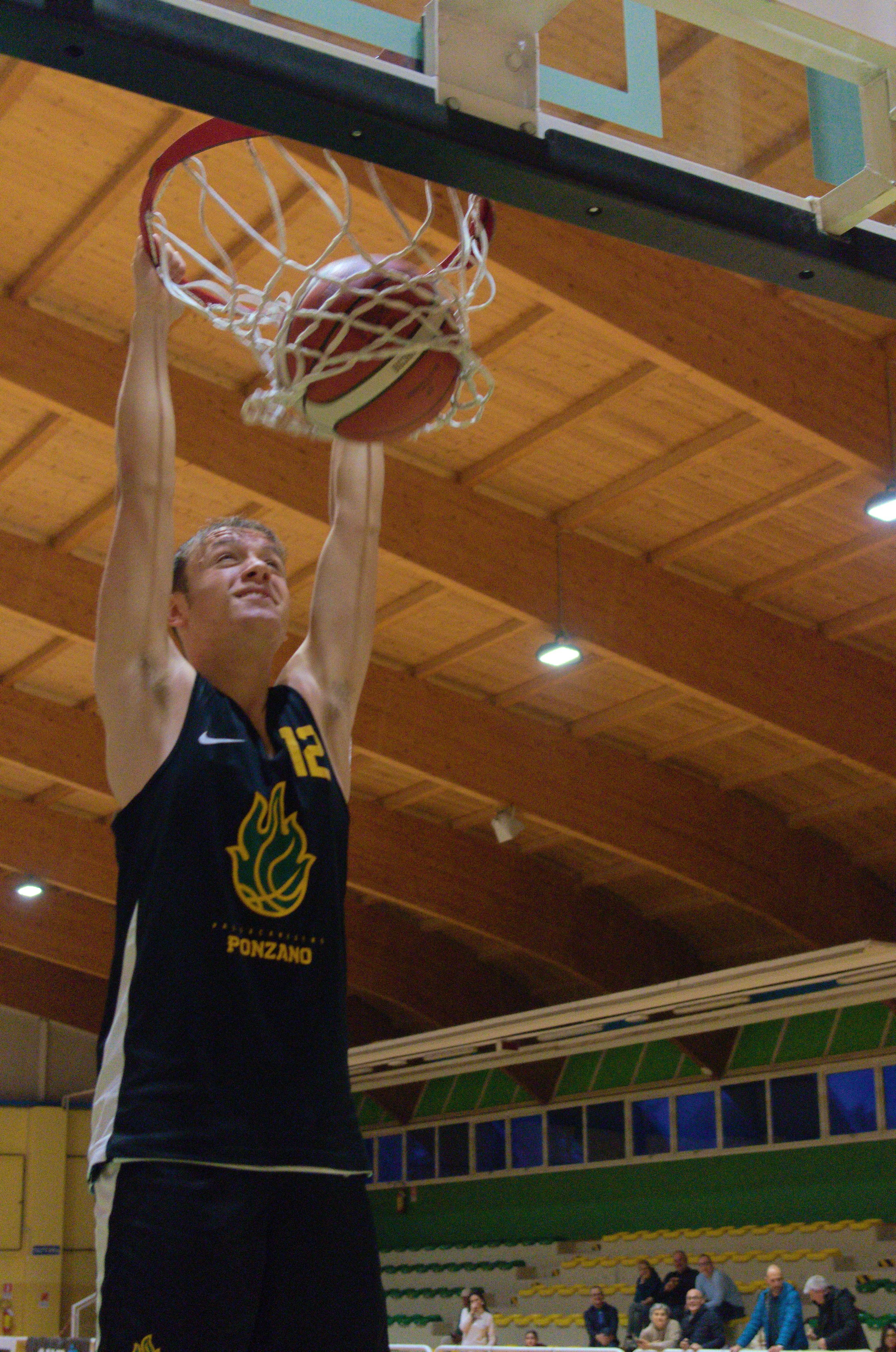 Giocatore di basket dell'u17 maschile si appende al canestro dopo una schiacciata nel Palacicogna, palazzetto della pallacanestro ponzano.