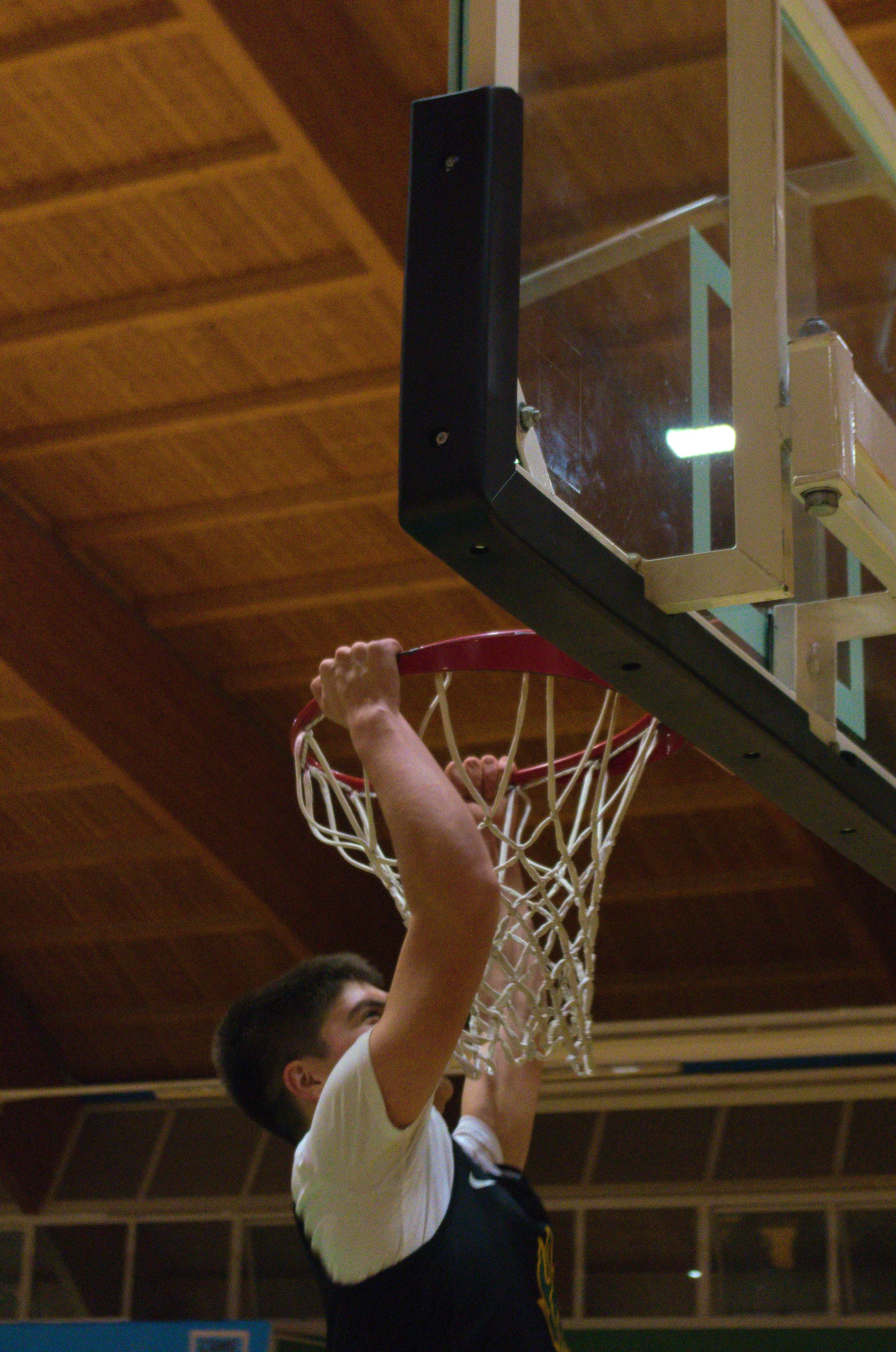 Giovane giocatore dell'u17 maschile della pallacanestro ponzano che sta facendo una schiacciata nel basket.
