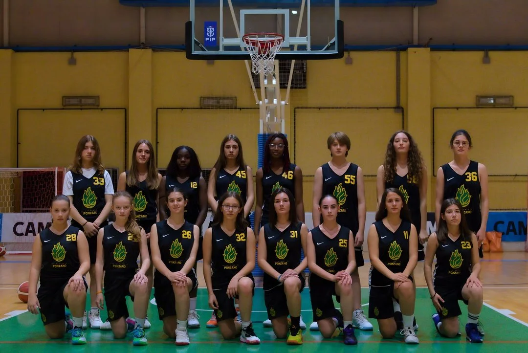Foto dell'under 14 femminile di pallacanestro ponzano in divisa nera con il logo di Ponzano, scattata in un campo da basket indoor.