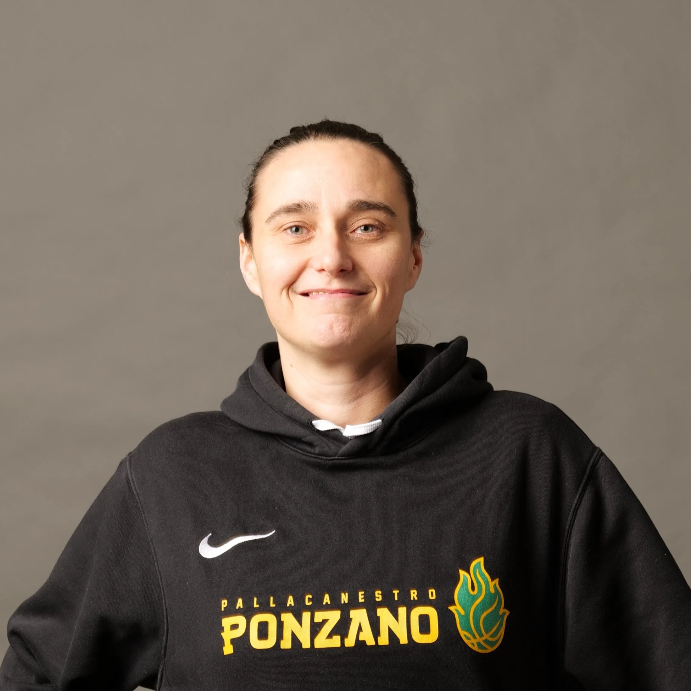 Lucija Drobac, allenatrice di basket, indossa felpa nera con logo di una squadra di pallacanestro Ponzano, sfondo grigio.