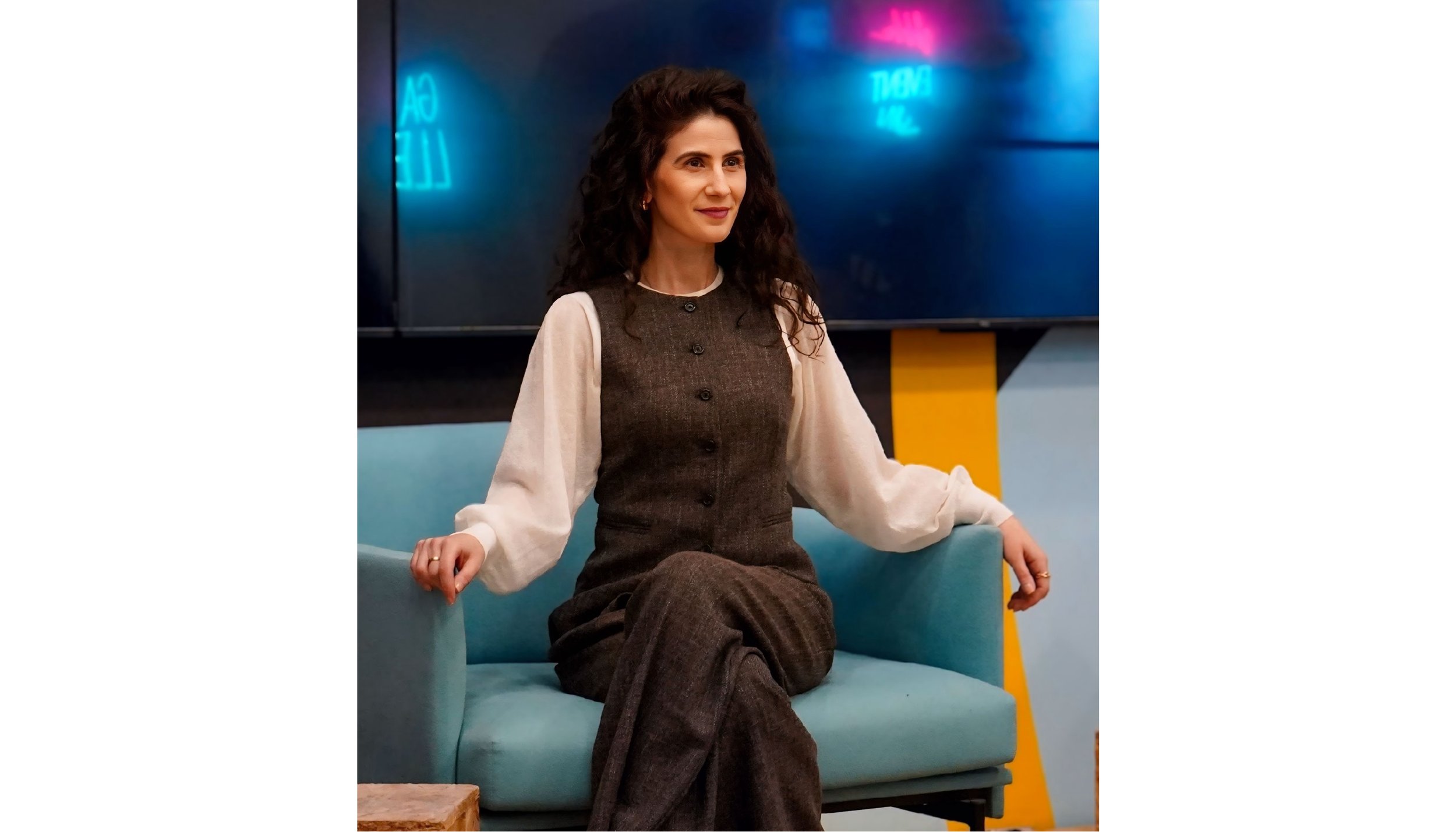 Hayriye Tekek seated in a modern chair, smiling in a professional portrait for her LinkedIn strategy and personal branding website.