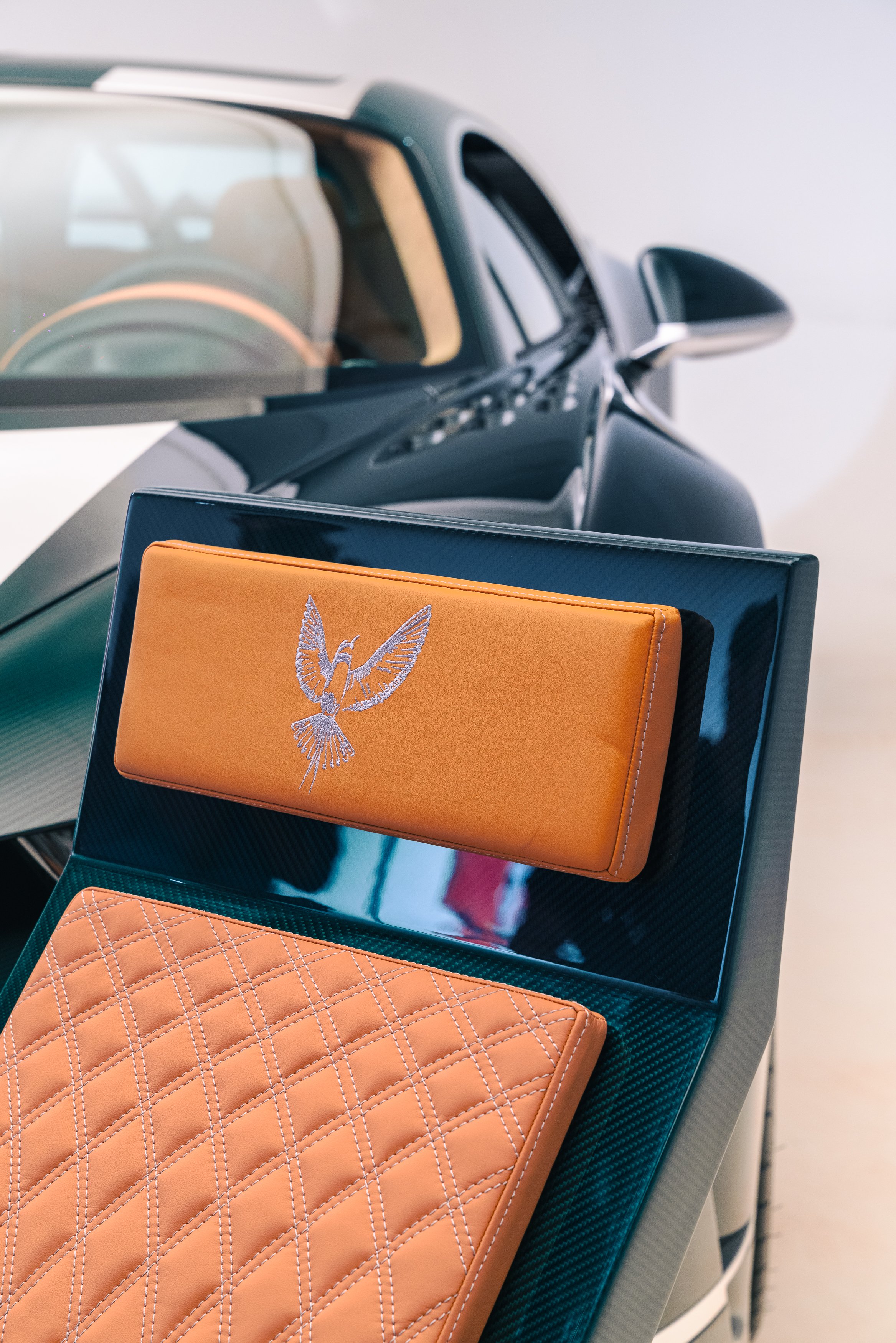 Close-up of a luxury car's interior and exterior, with a focus on the dashboard and a model of a bird logo on the dashboard.