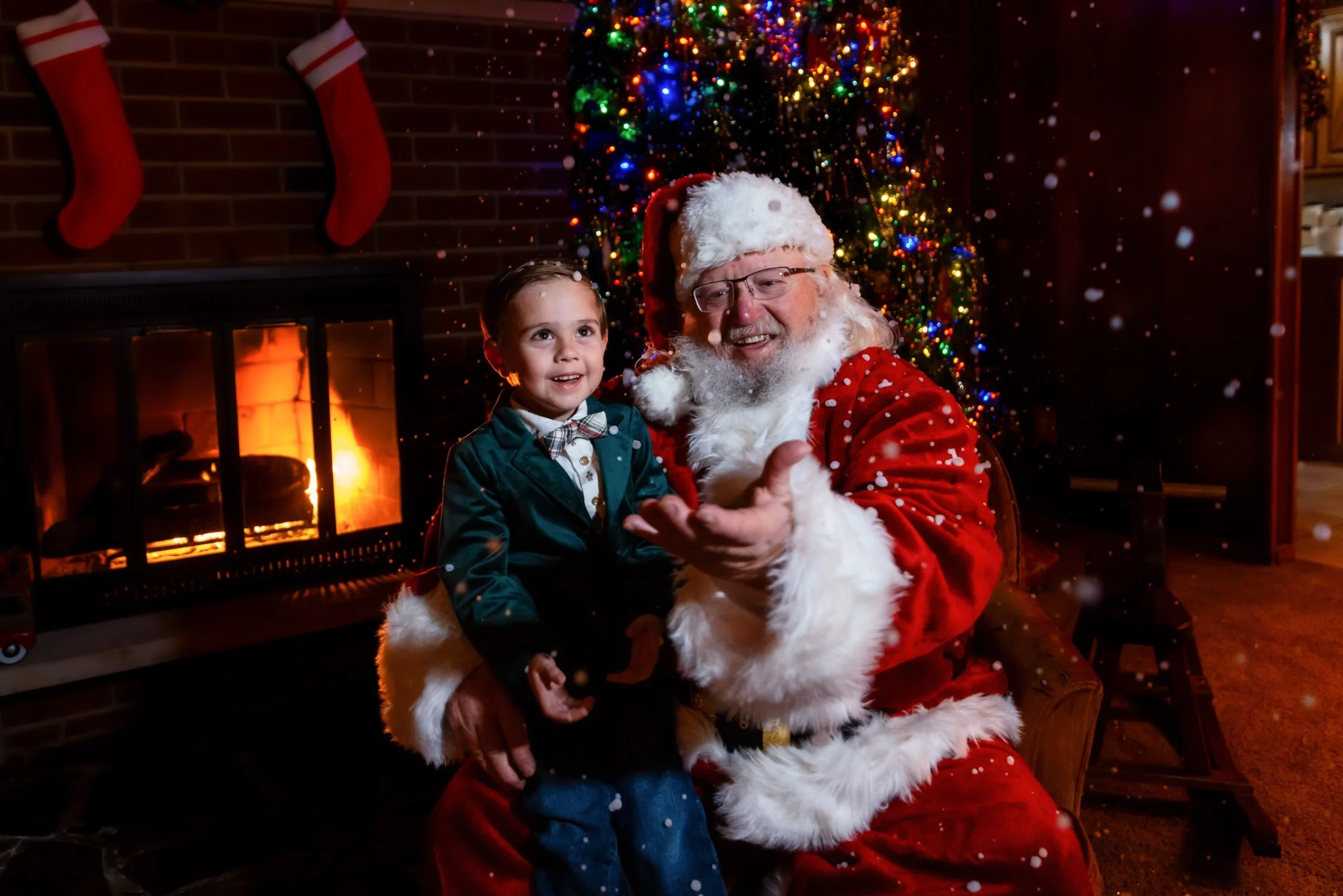 Santa reaching toward a young boy as indoor snow falls inside the cabin