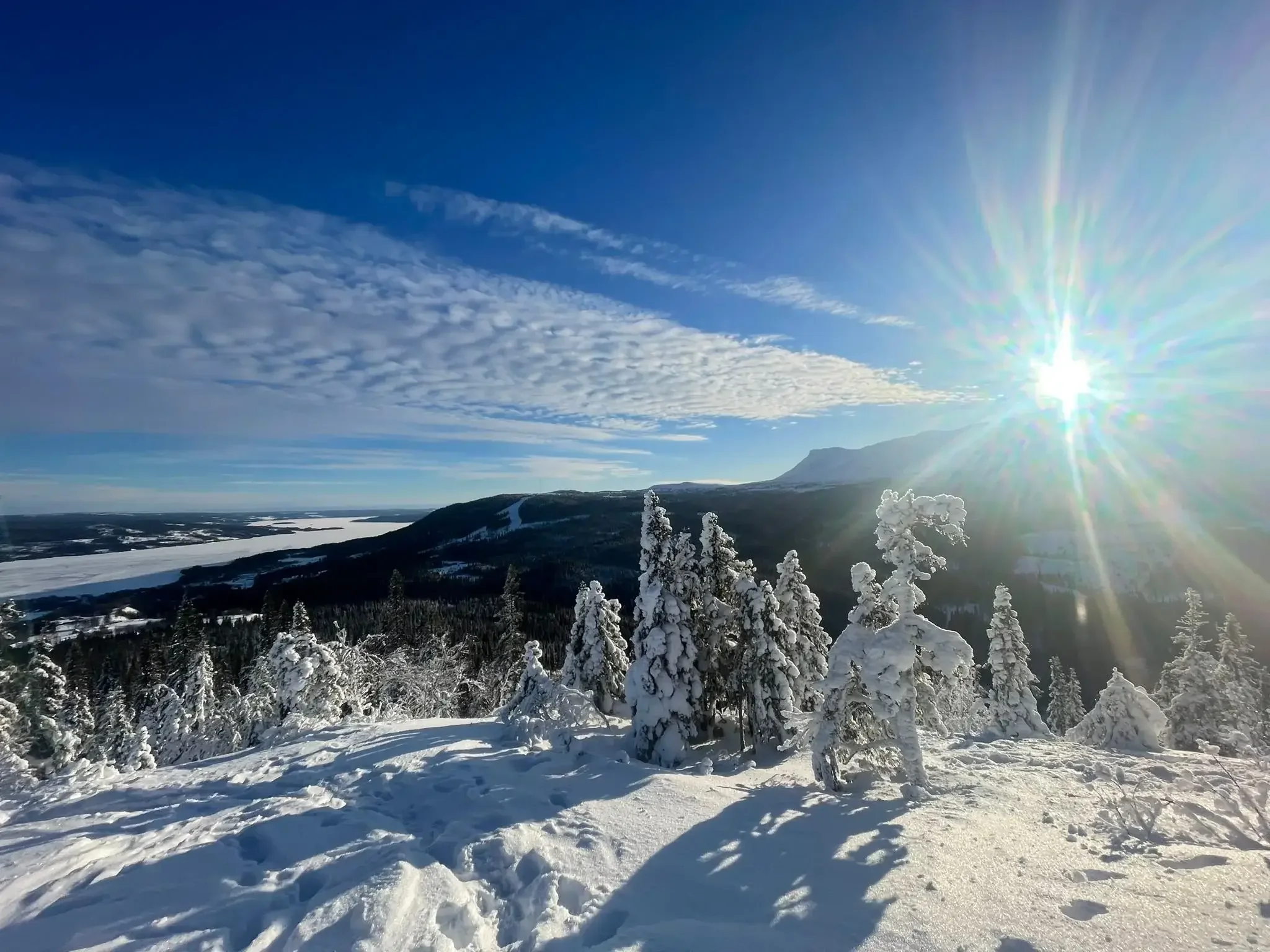 En snowboardåkare och en skidåkare i matchande rosa och gula kläder förbereder sig i en snötäckt backe i Huså, med en lift och skog i bakgrunden.