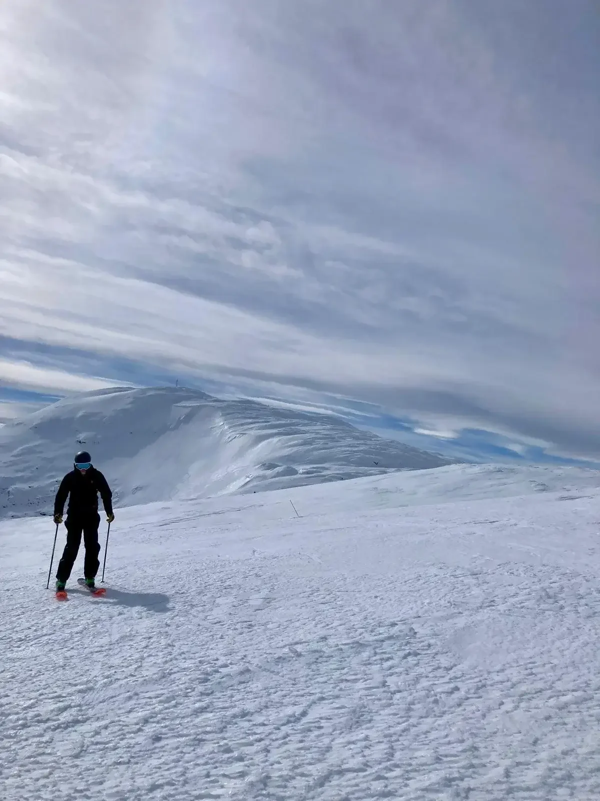 En skidåkare i siluett mot en mäktig snötäckt bergsvägg.