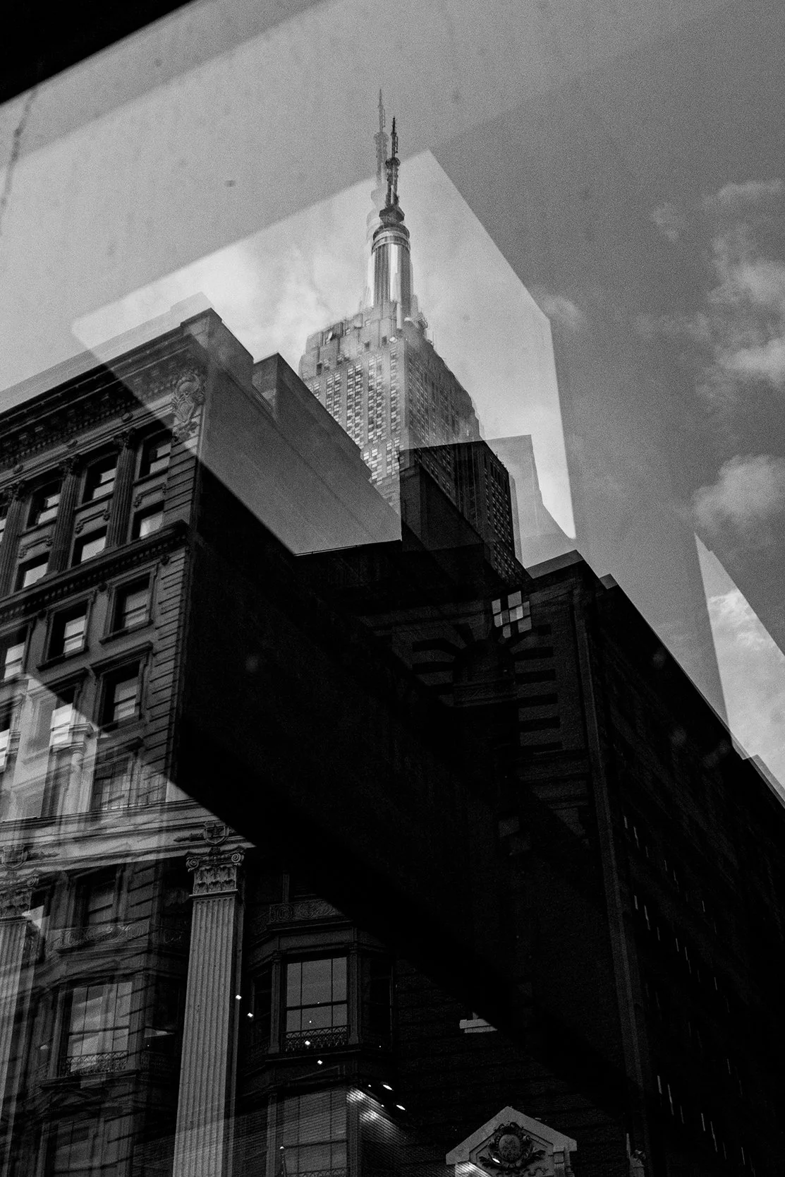 Reflection of a skyscraper, the Empire State Building, in a glass window with surrounding buildings.